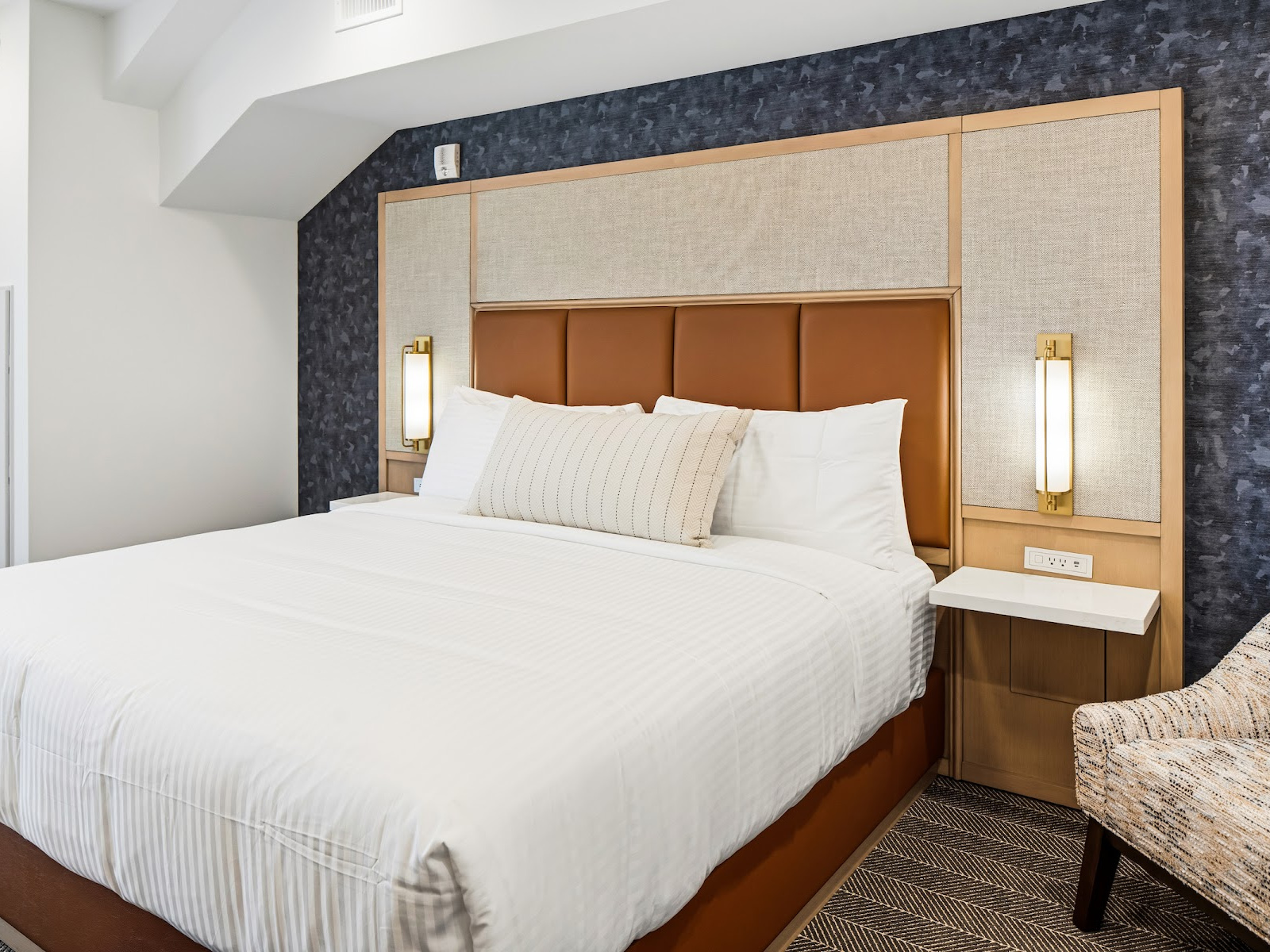 Harbor Suite king bedroom at Wilson’s Cove with upholstered headboard and coastal blue accents.