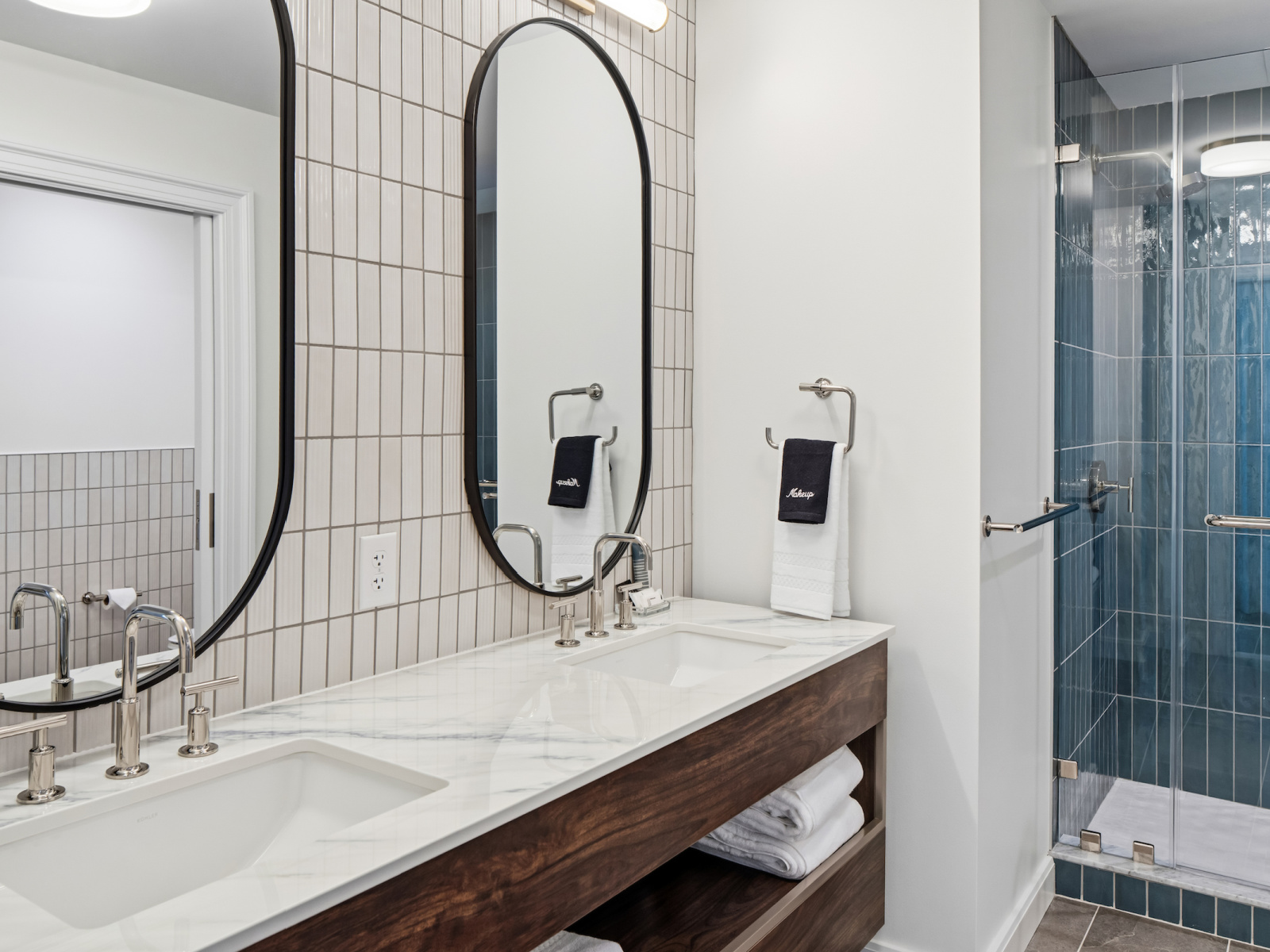 Harbor Suite bathroom at Wilson’s Cove with double vanity and blue tile walk-in shower.