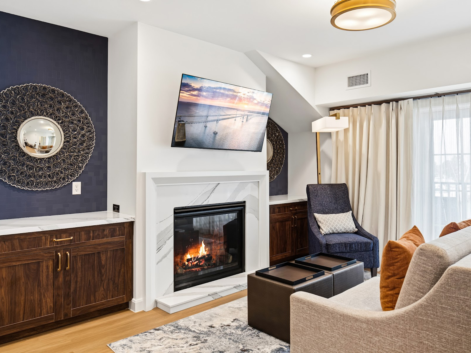 Wilson’s Cove Harbor Suite living room with fireplace, coastal furnishings and private balcony.