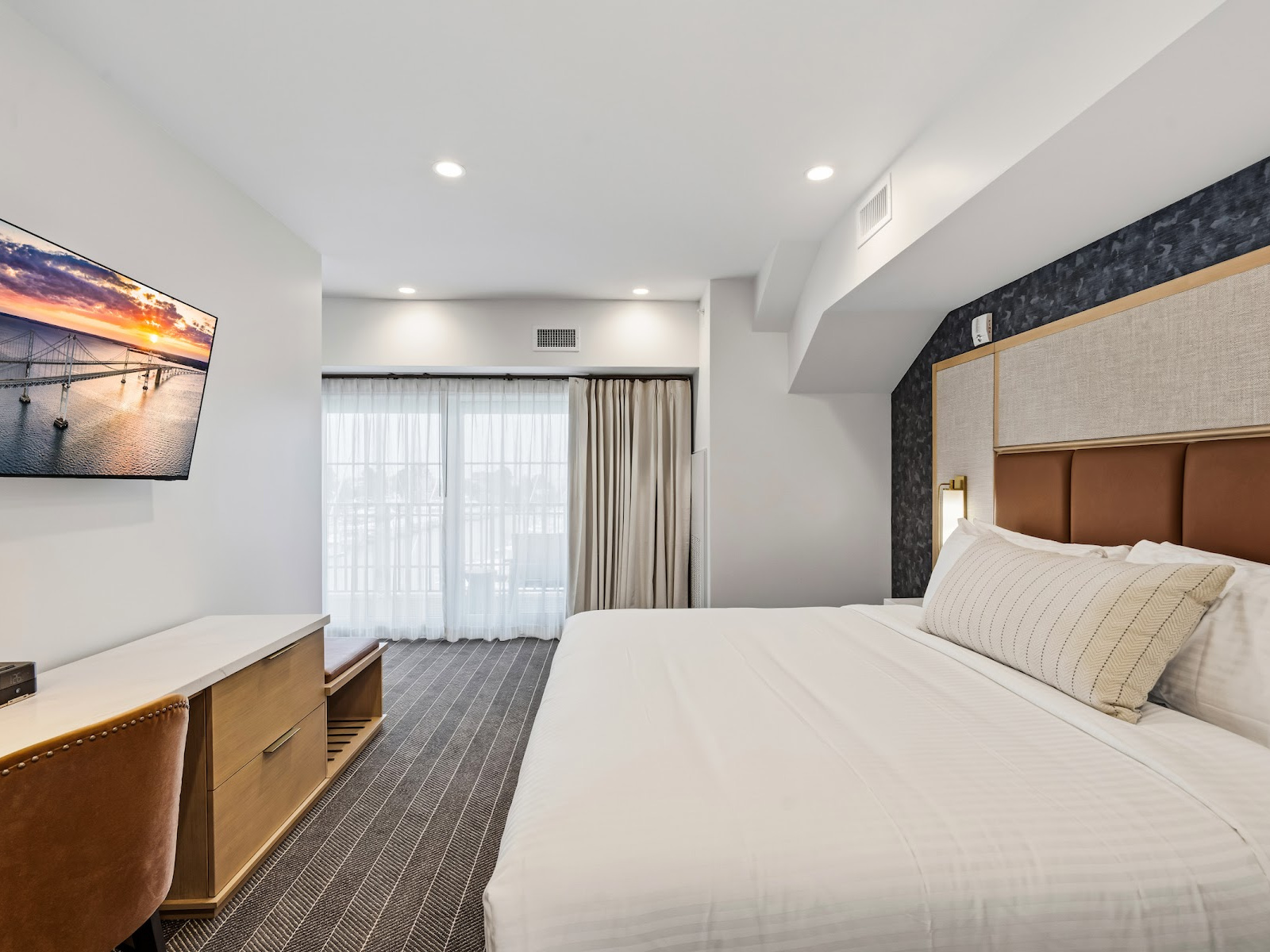 Wilson’s Cove Harbor Suite king bedroom with desk, television and private balcony access.