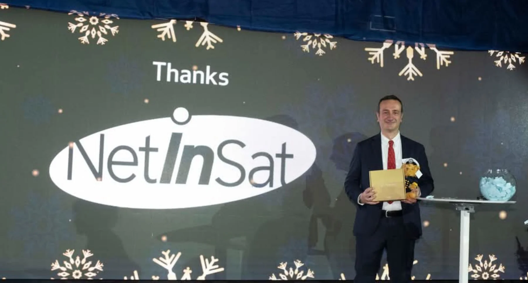 NetInSat founder on stage in front of the NetInSat logo at a yachting industry event