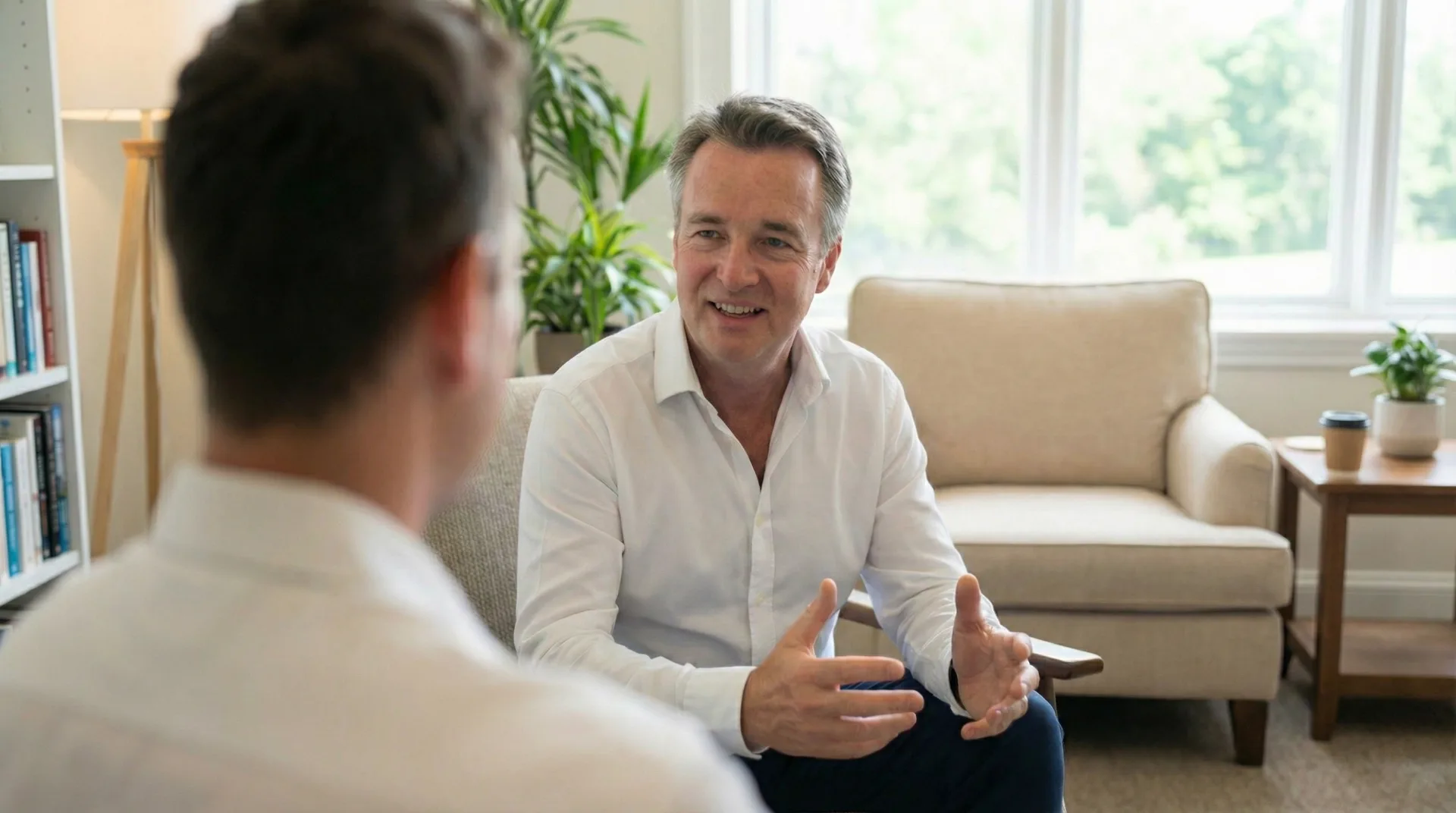 Dr. Andreas Hartung sitzt in einer Lounge und berät einen Kunden für das Thema Gesundheitsmanagement.