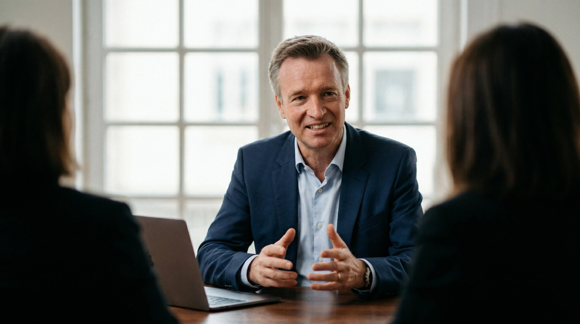 Dr. Andreas Hartung, der Gründer der H2A Hartung Healthcare Advisory sitzt in einem Anzug am Schreibtisch während einem Kundengespräch