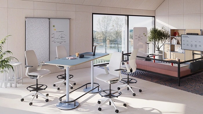 Collaborative office table with rolling chairs and whiteboards in a bright, open workspace environment