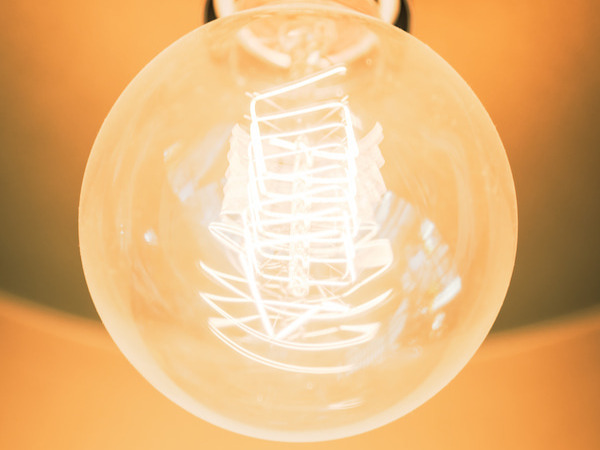 Gros plan sur une ampoule à filament LED allumée avec lumière chaude dorée.