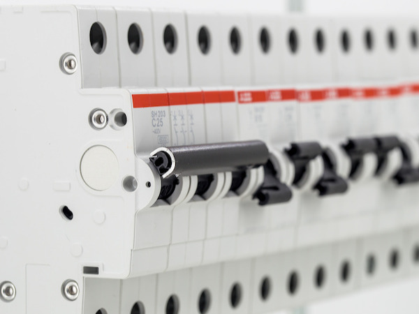 Gros plan sur une rangée de disjoncteurs modulaires ABB dans un tableau électrique.