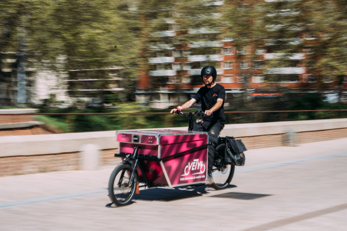 Électricien roulant en centre-ville de Toulouse avec son vélo cargo aux couleurs de Vety.