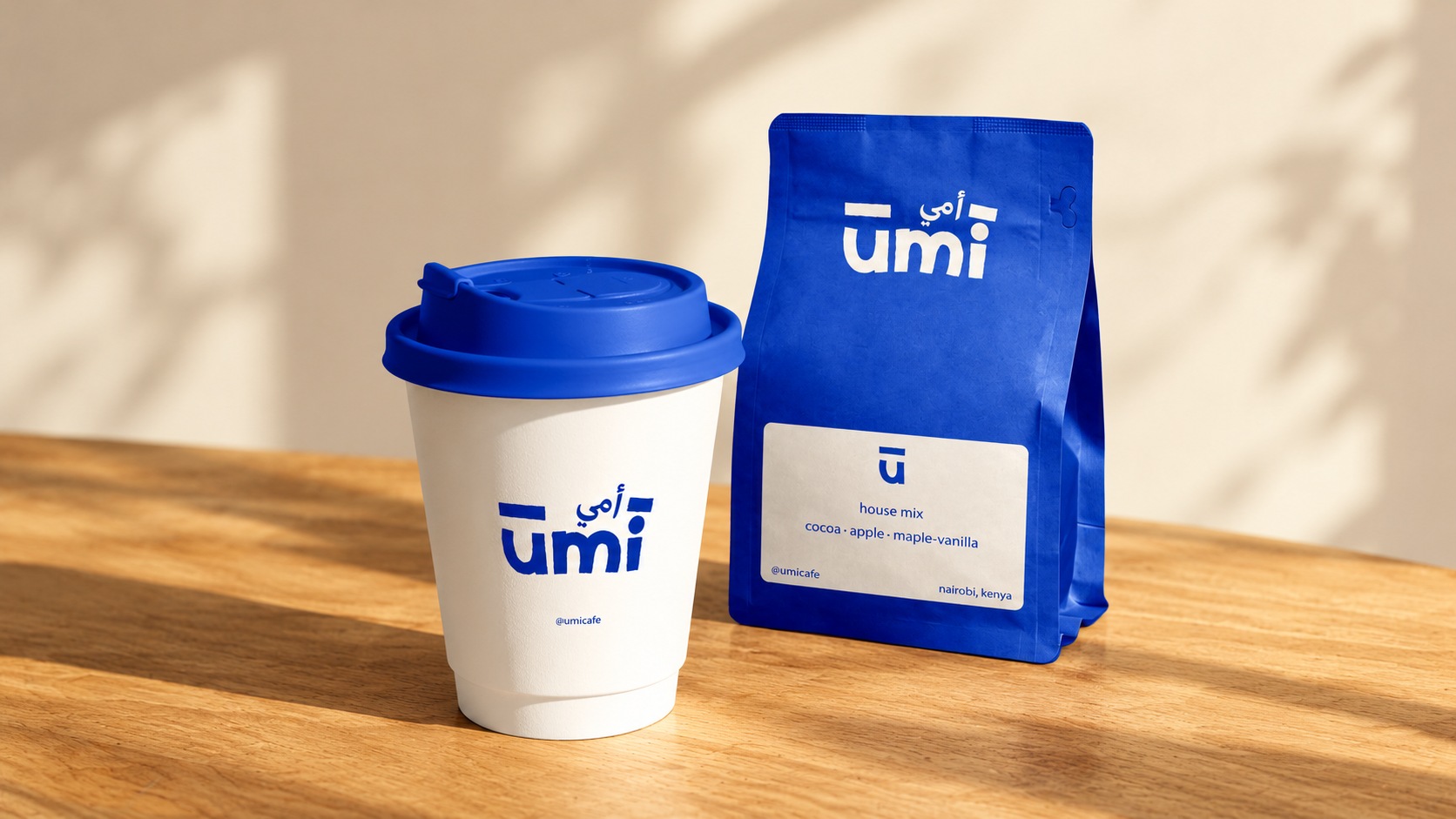 Umi branded takeaway cup and blue coffee bag together on a wooden surface