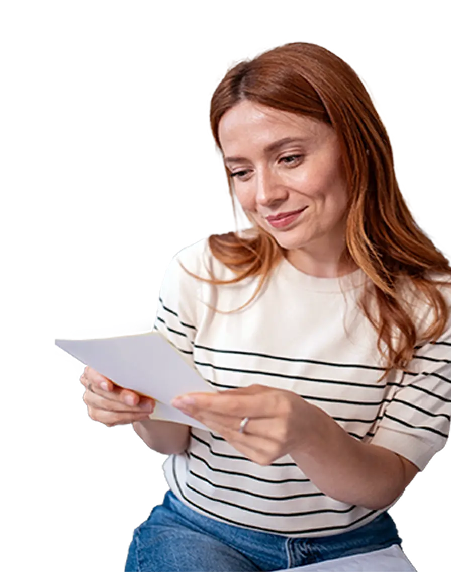 Woman with red hair wearing striped shirt holding and looking at a white paper.