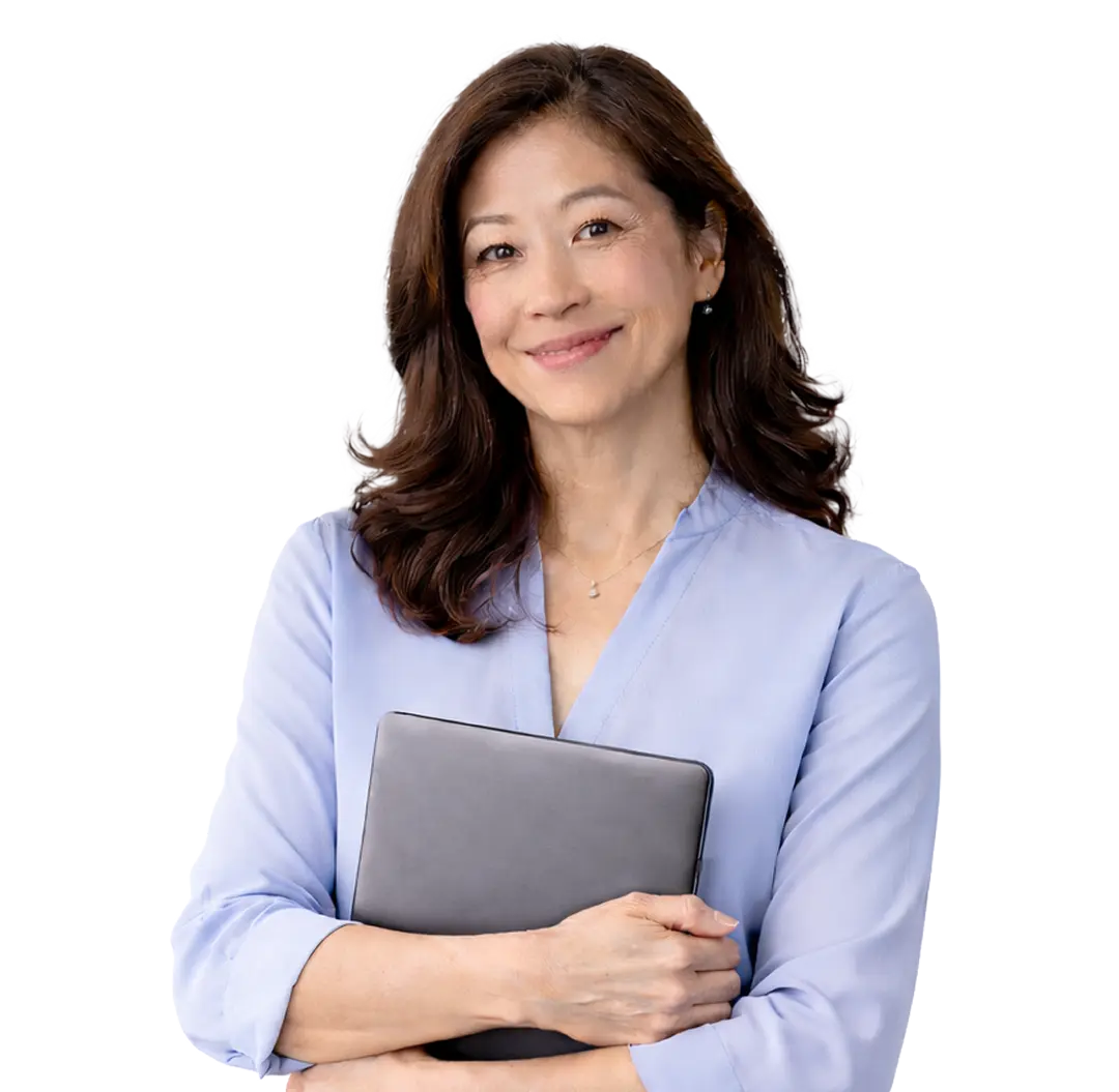 Smiling Asian woman with wavy hair holding a closed laptop and wearing a light blue blouse.