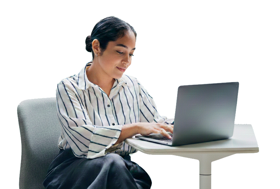 Woman in a striped shirt sitting at a table typing on a laptop.