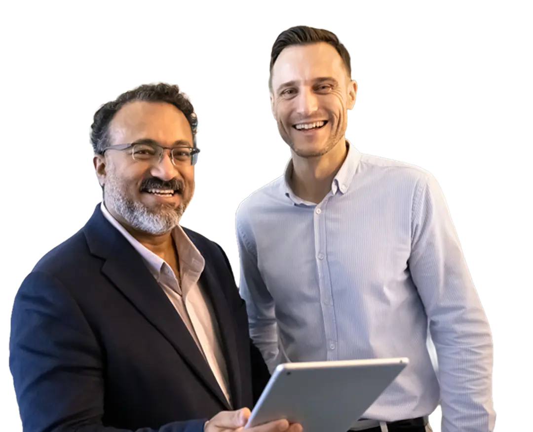 Two men smiling, one holding a tablet, dressed in business attire with no background.
