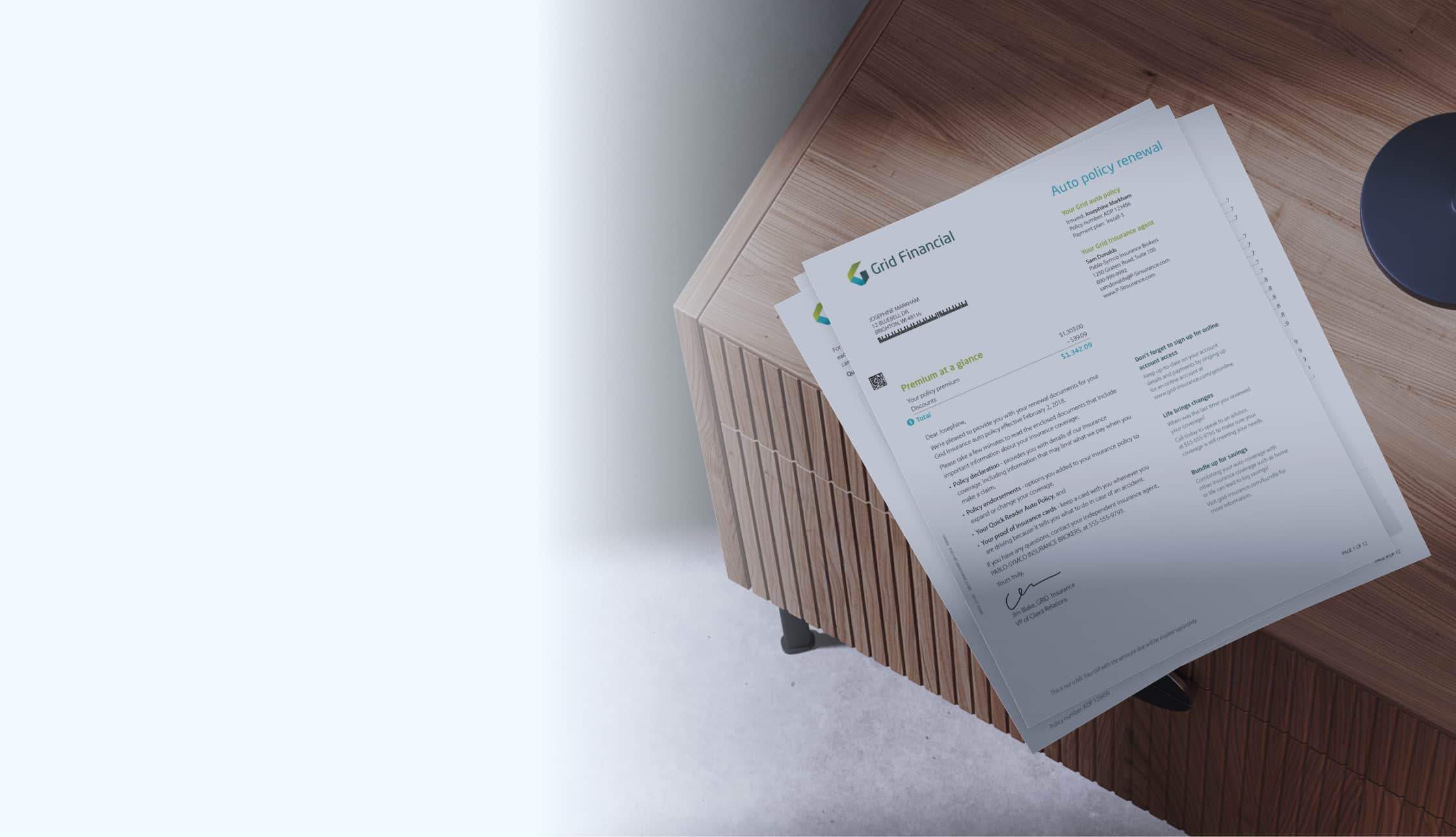 Auto policy renewal documents on wooden desk from Grid Financial with premium details.