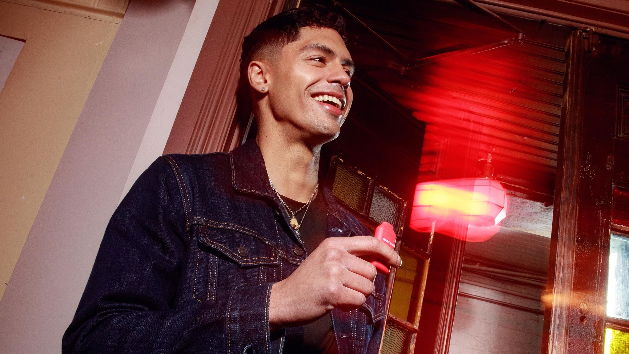 Person holding a Pastime disposable cannabis vape in moody red light