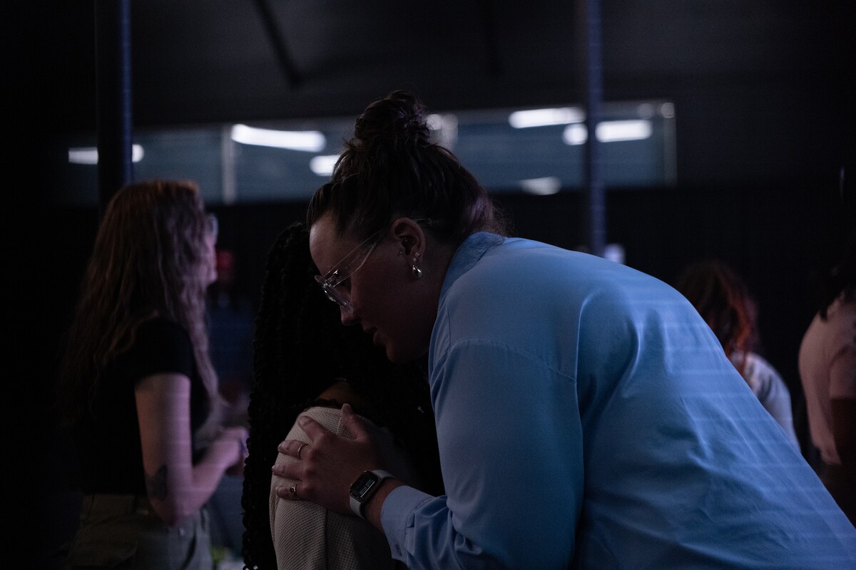 Woman with hands on another woman praying