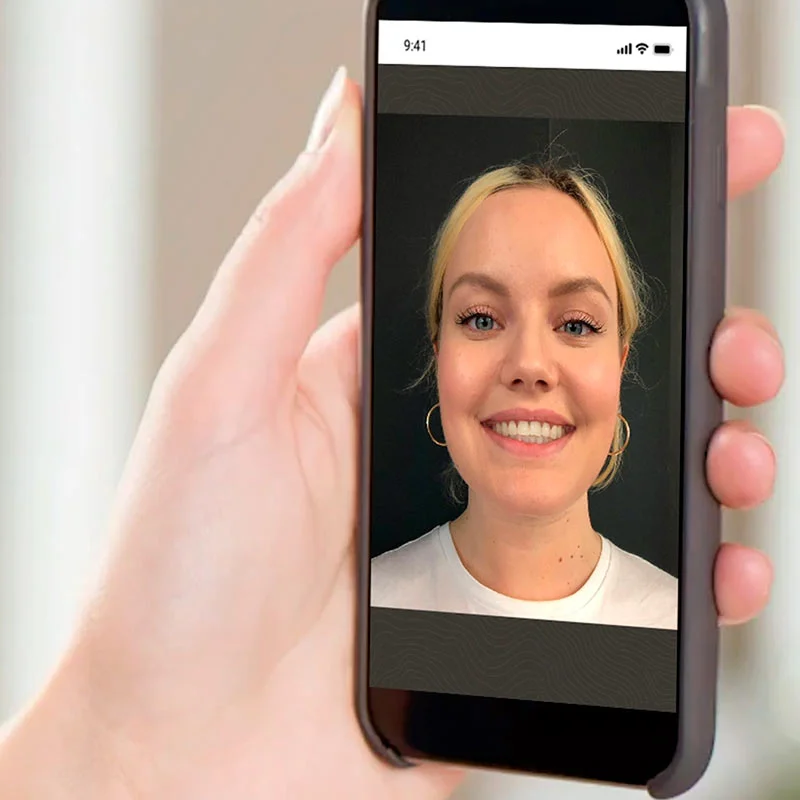 A person holding a cell phone with a woman's face on it.