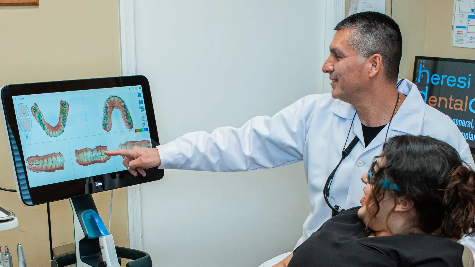 A man pointing at a computer screen with a smile on his face.