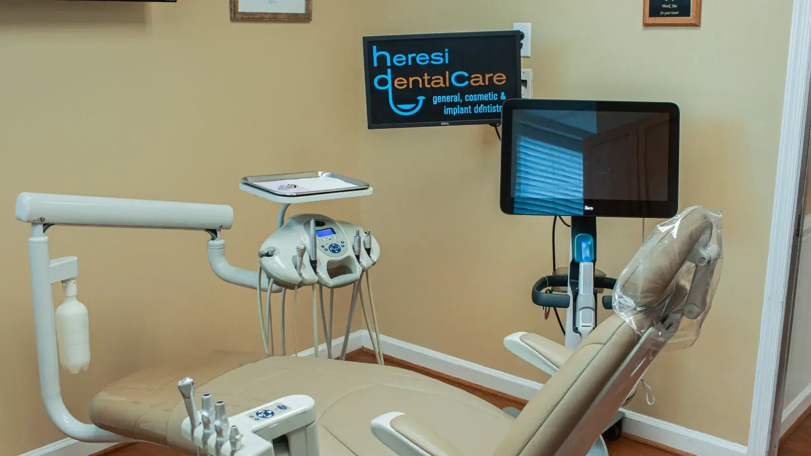 A dental room with a monitor, chair, and other medical equipment.