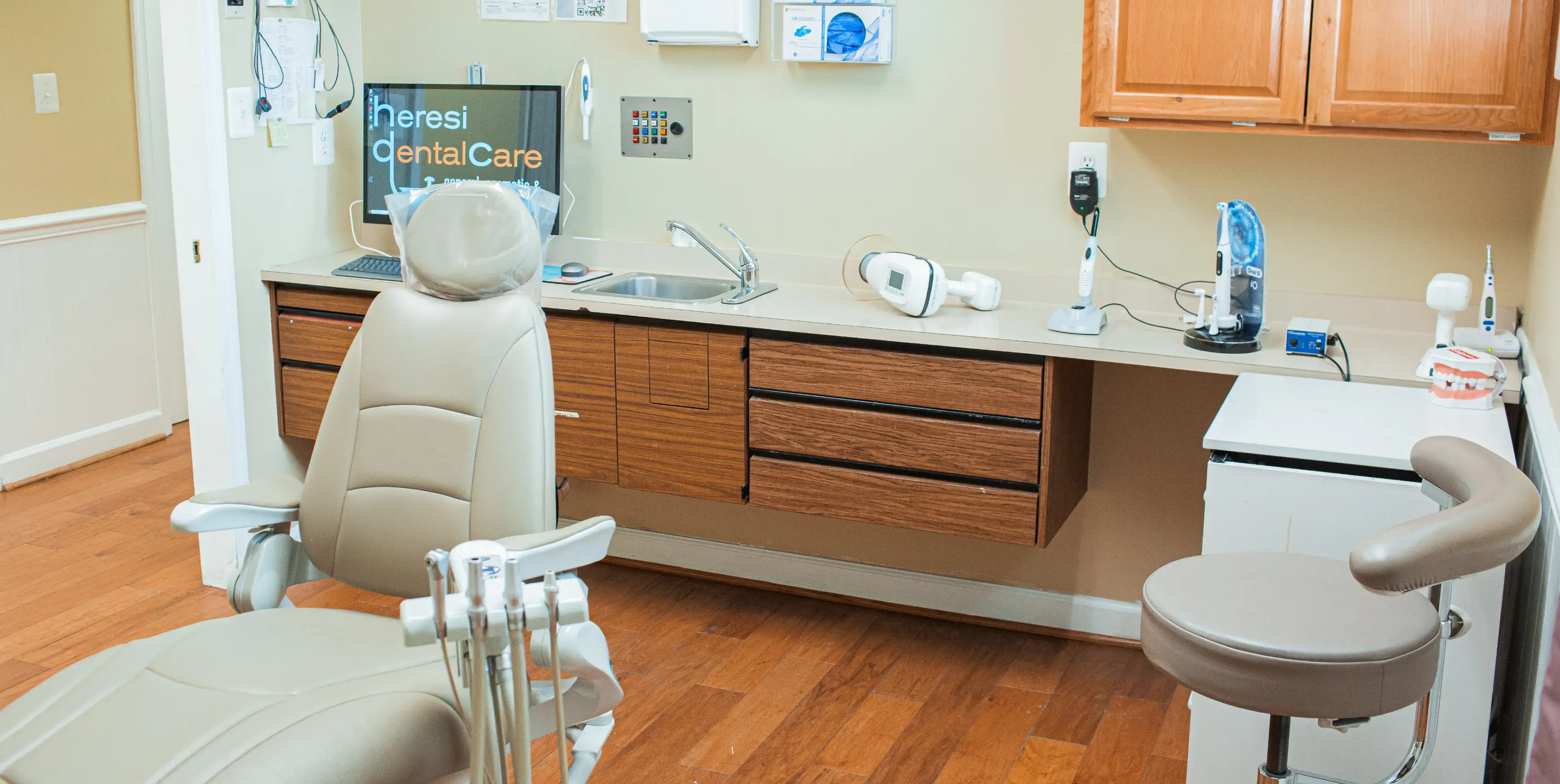 A dentist's office with a dental chair and sink.