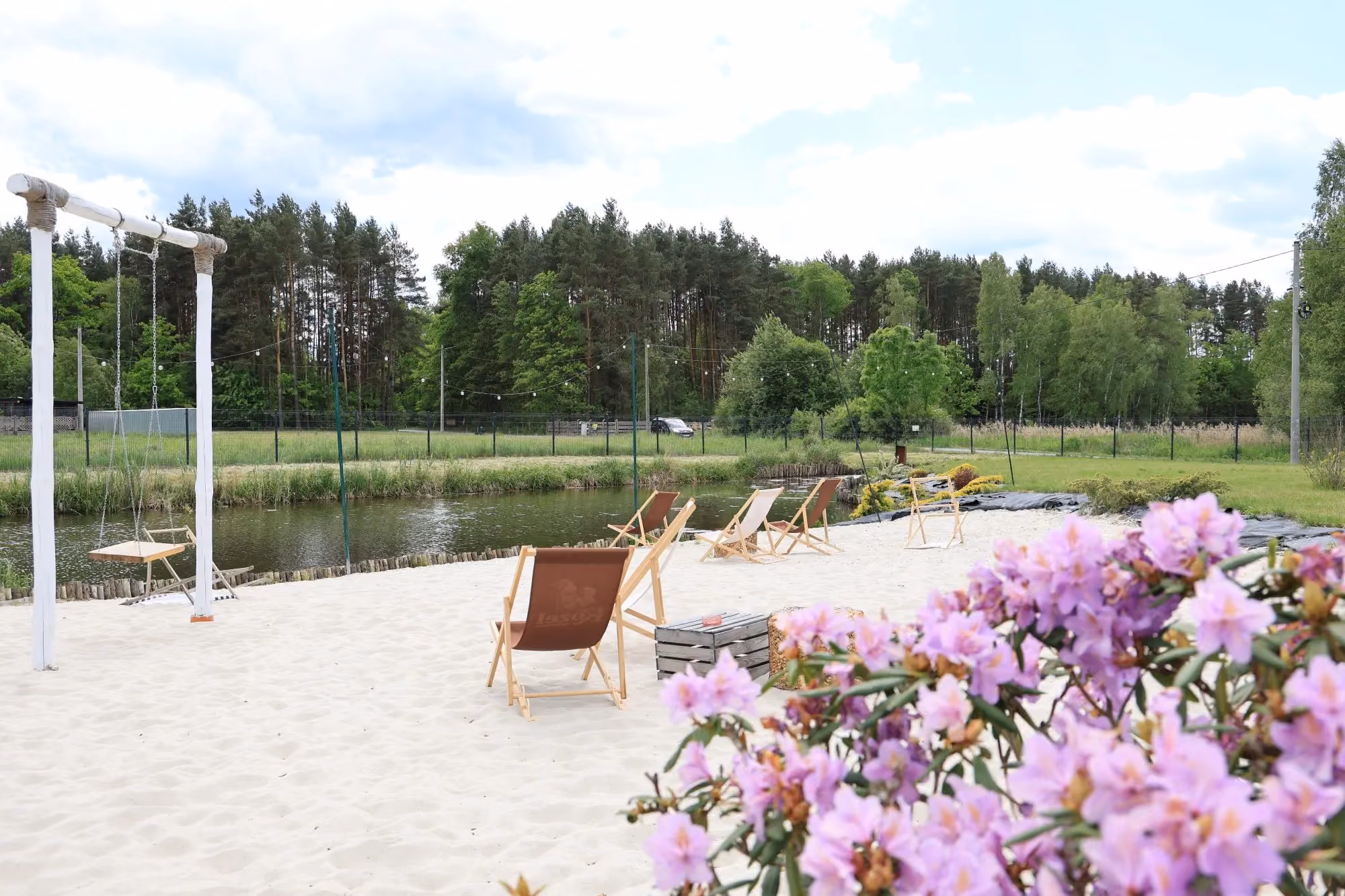 Piaszczysta plaża z leżakami nad stawem na terenie Smażalni i Łowiska BAKS, idealna do wypoczynku na łonie natury.