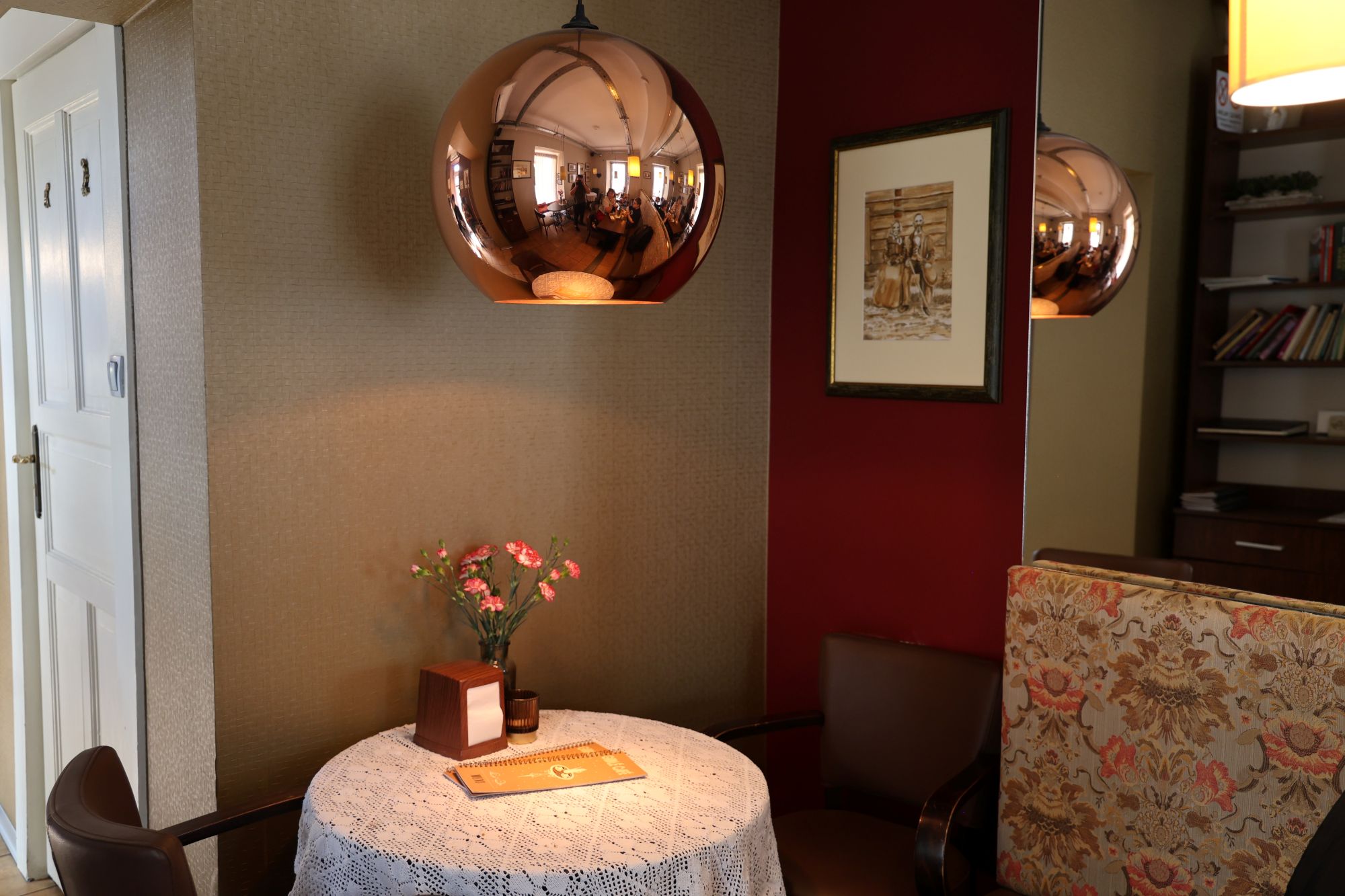 Elegancki kącik wypoczynkowy w Cafe Gidle z dekoracyjną lampą, stolikiem i kwiatami.