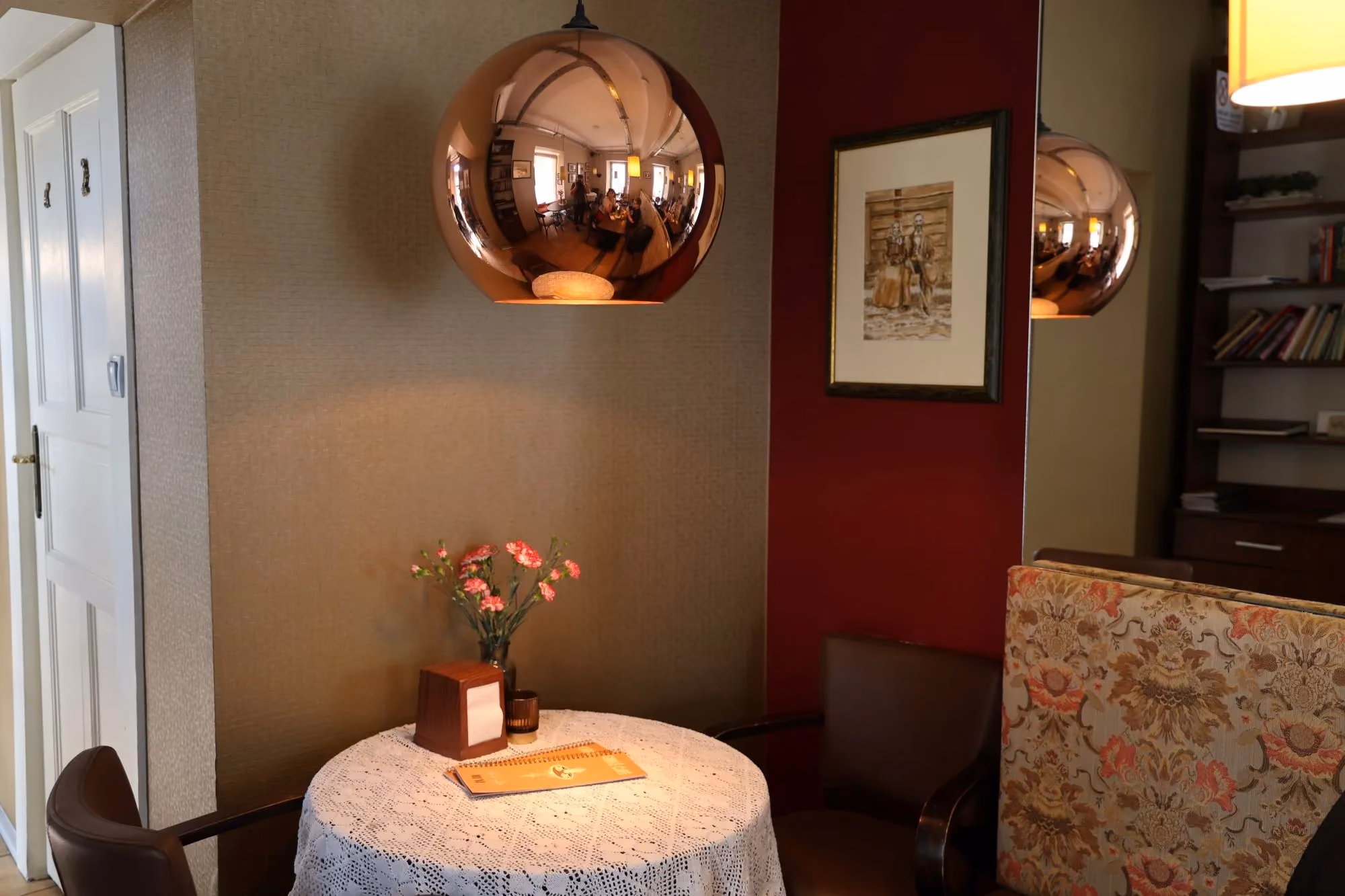 Elegancki kącik wypoczynkowy w Cafe Gidle z dekoracyjną lampą, stolikiem i kwiatami.