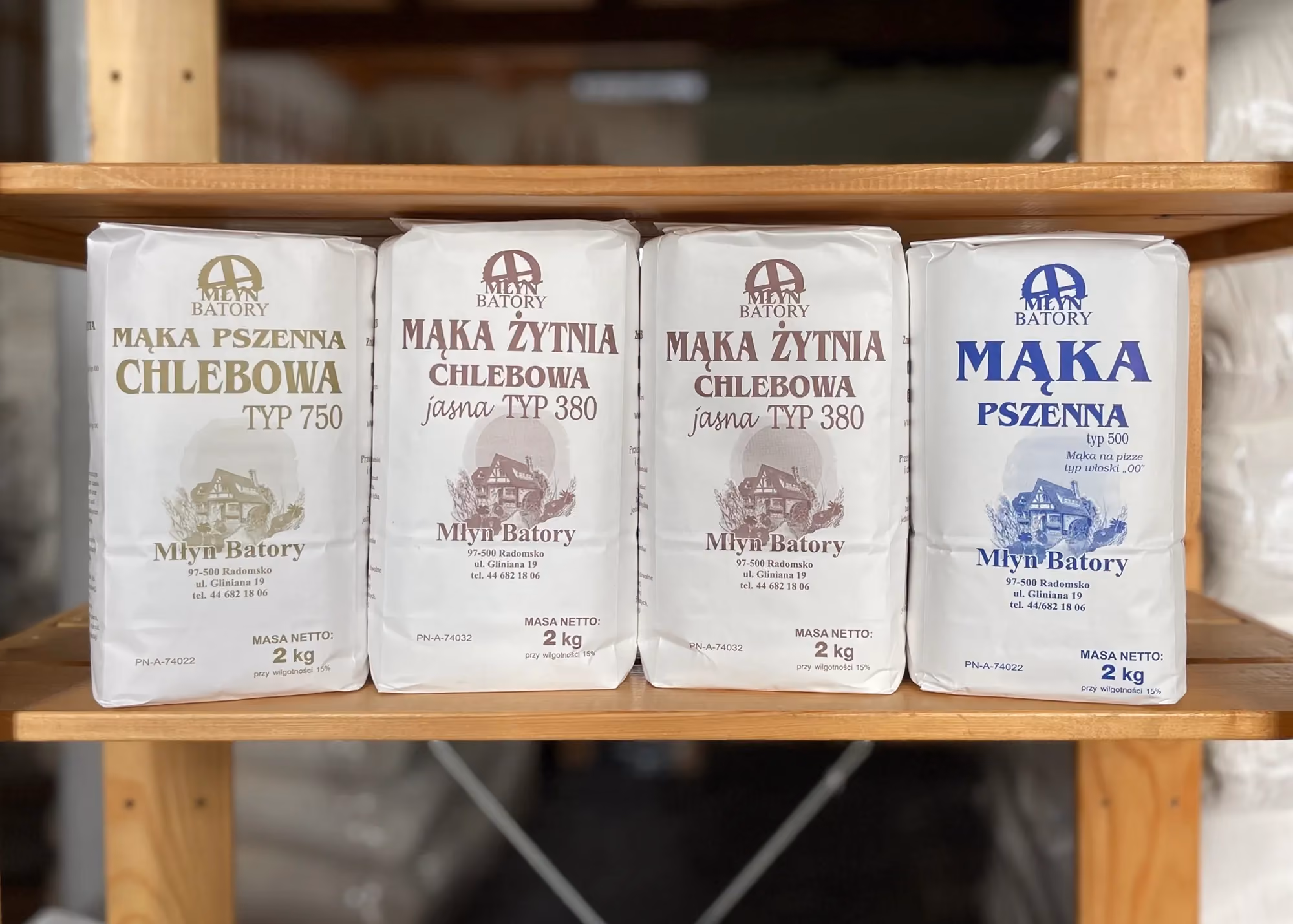 Różne rodzaje mąki marki Młyn Batory ustawione na drewnianej półce