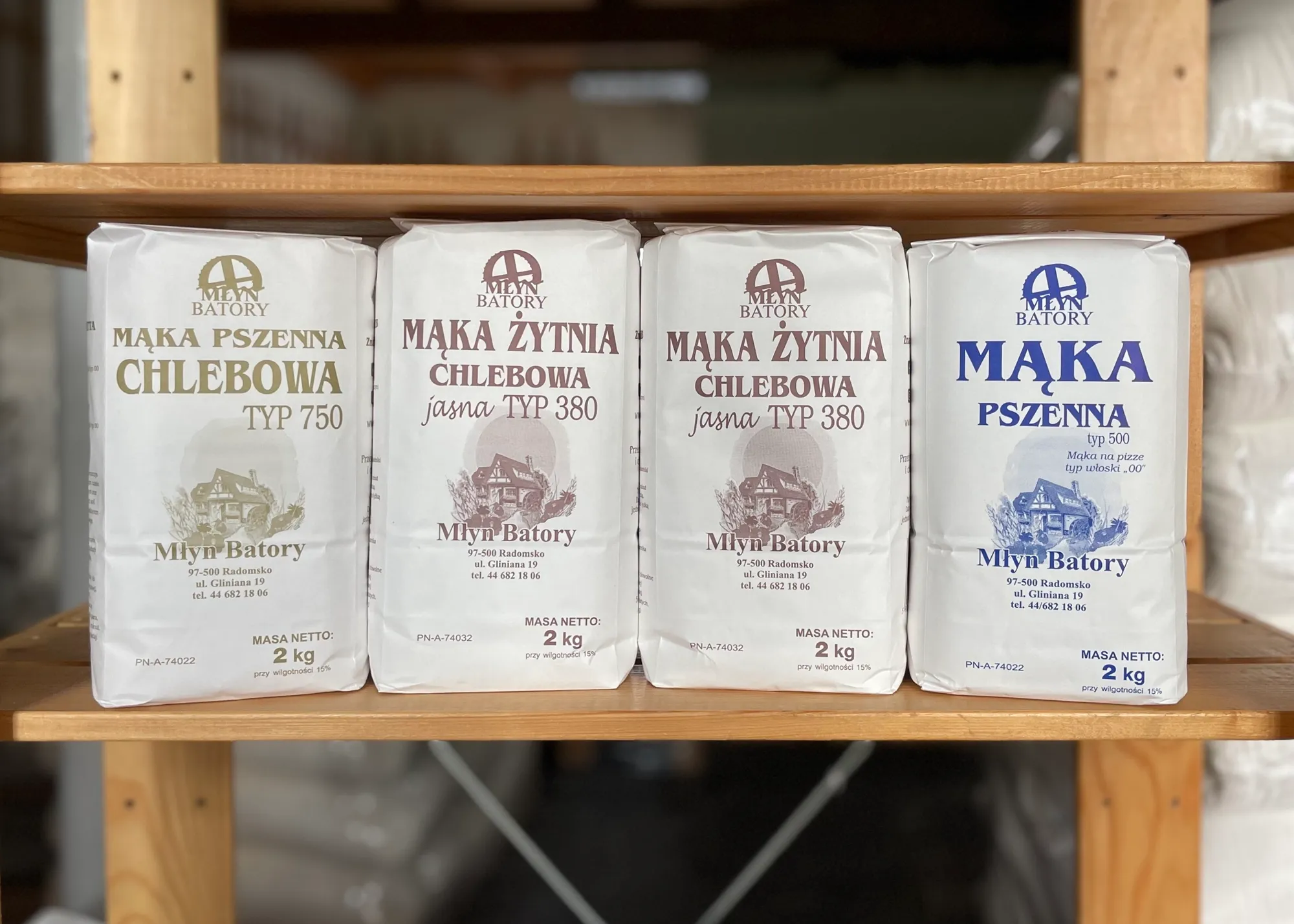 Różne rodzaje mąki marki Młyn Batory ustawione na drewnianej półce