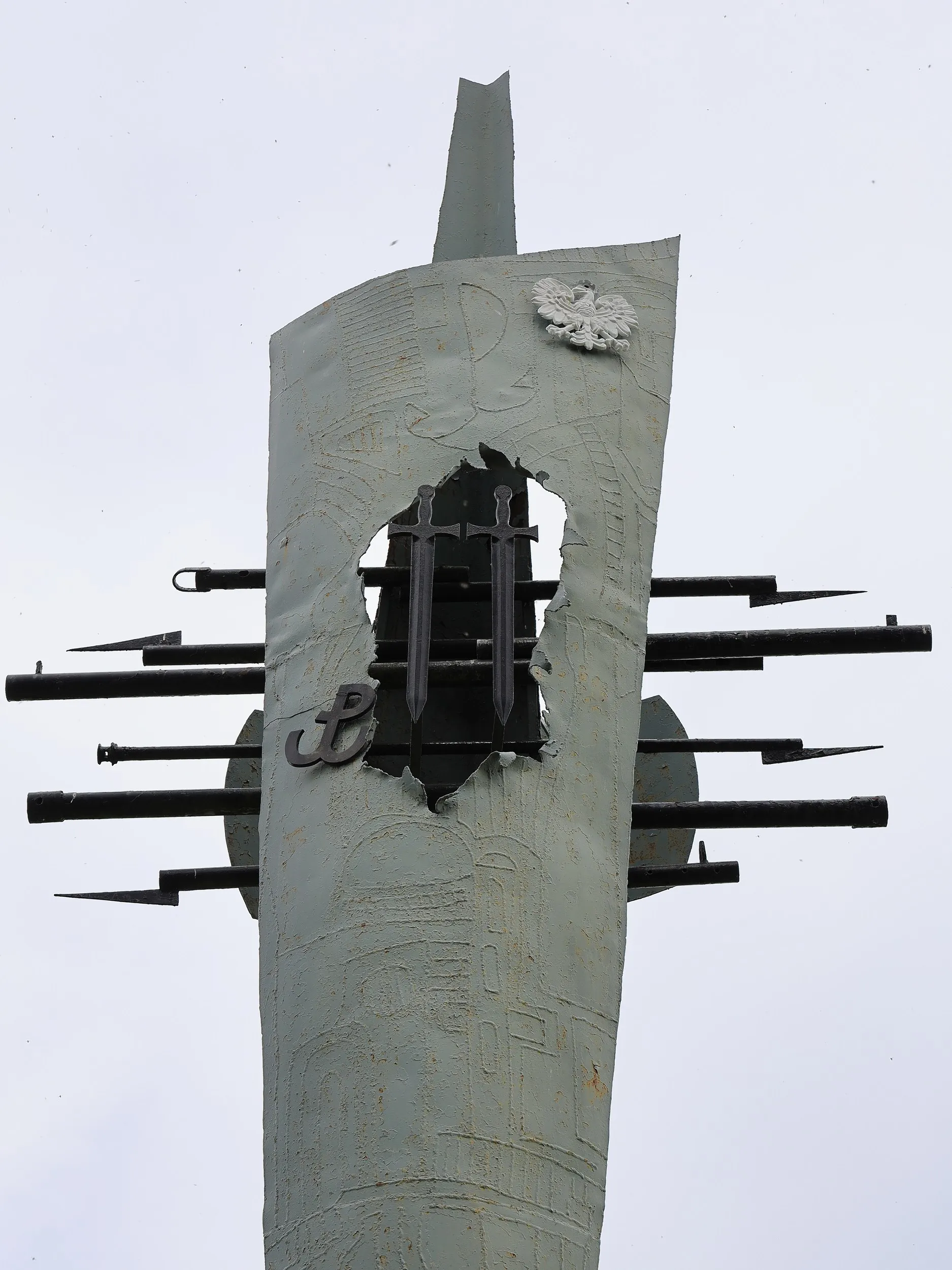 Zbliżenie na centralny element monumentu. W metalowej konstrukcji umieszczono symbol Polski Walczącej, dwa pionowe miecze oraz wizerunek orła. Kompozycja nawiązuje do walki o niepodległość i działalności polskiego ruchu oporu podczas II wojny światowej