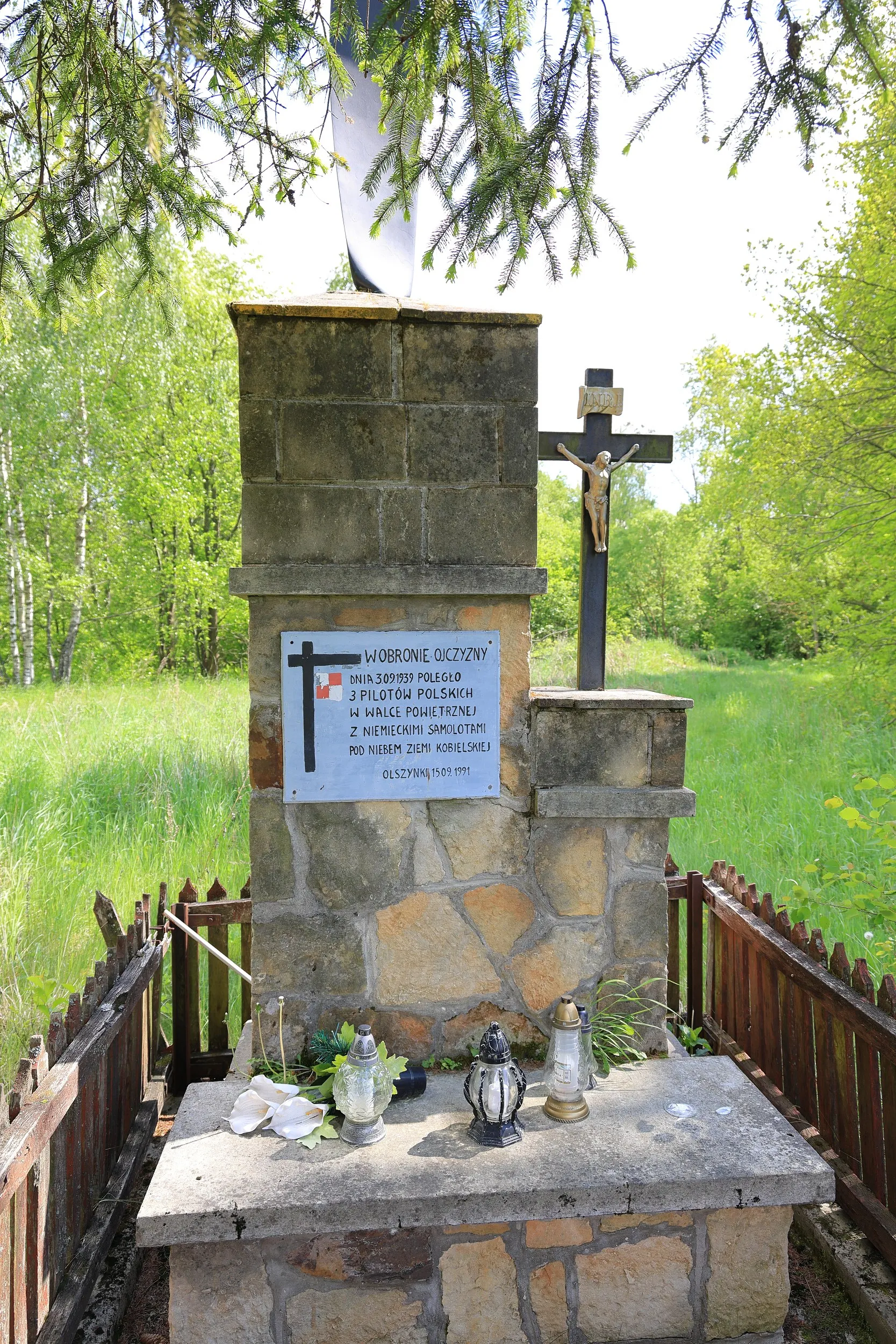 Miejsce pamięci ku czci polskich lotników poległych we wrześniu 1939 roku, otoczone drewnianym ogrodzeniem i położone wśród zieleni.
