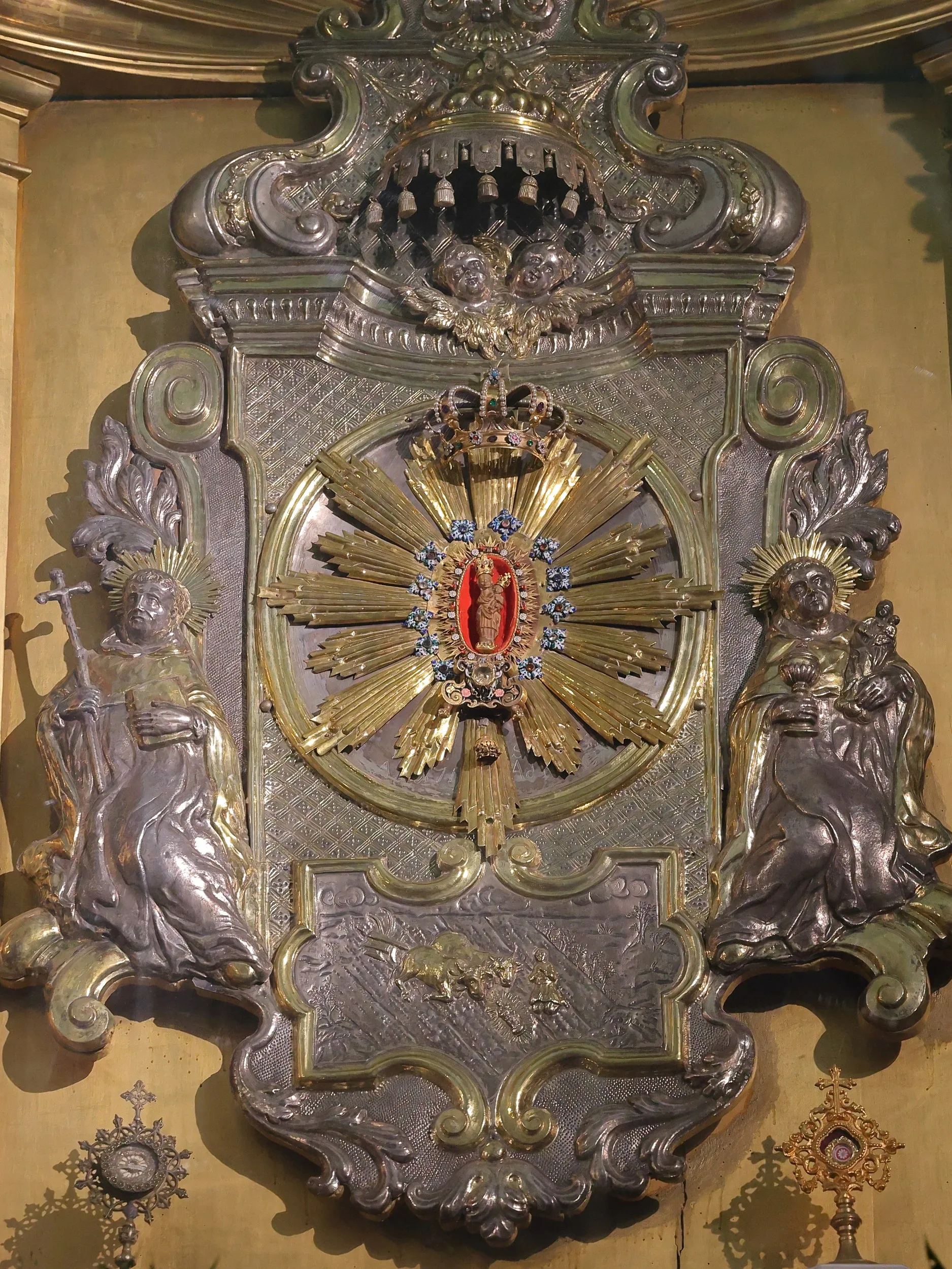Zbliżenie centralnej części ołtarza z figurami świętych oraz otoczoną promienistą dekoracją figurką Matki Bożej z Dzieciątkiem.