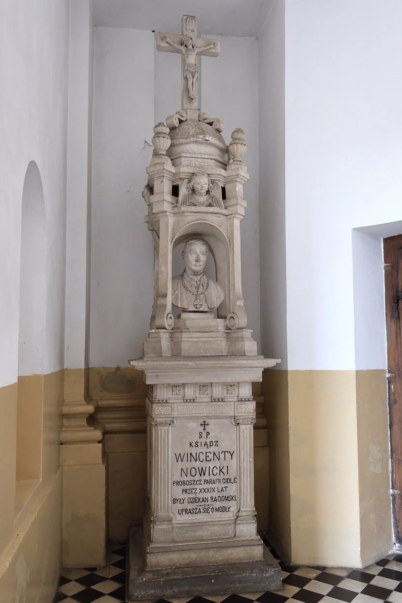 Kamienny pomnik księdza Wincentego Nowickiego we wnętrzu świątyni. Na cokole znajduje się tablica pamiątkowa z inskrypcją.