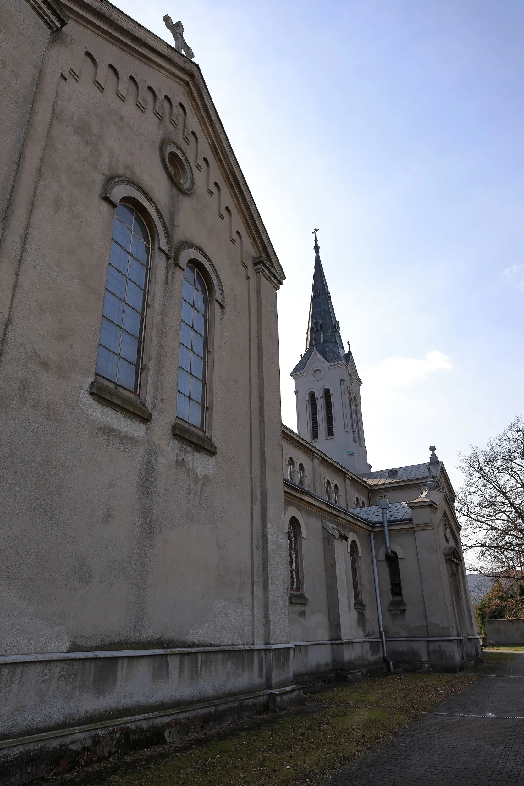 Fragment bocznej elewacji kościoła z wysokimi oknami i częścią wieży. Widoczne są detale architektoniczne oraz rynny.