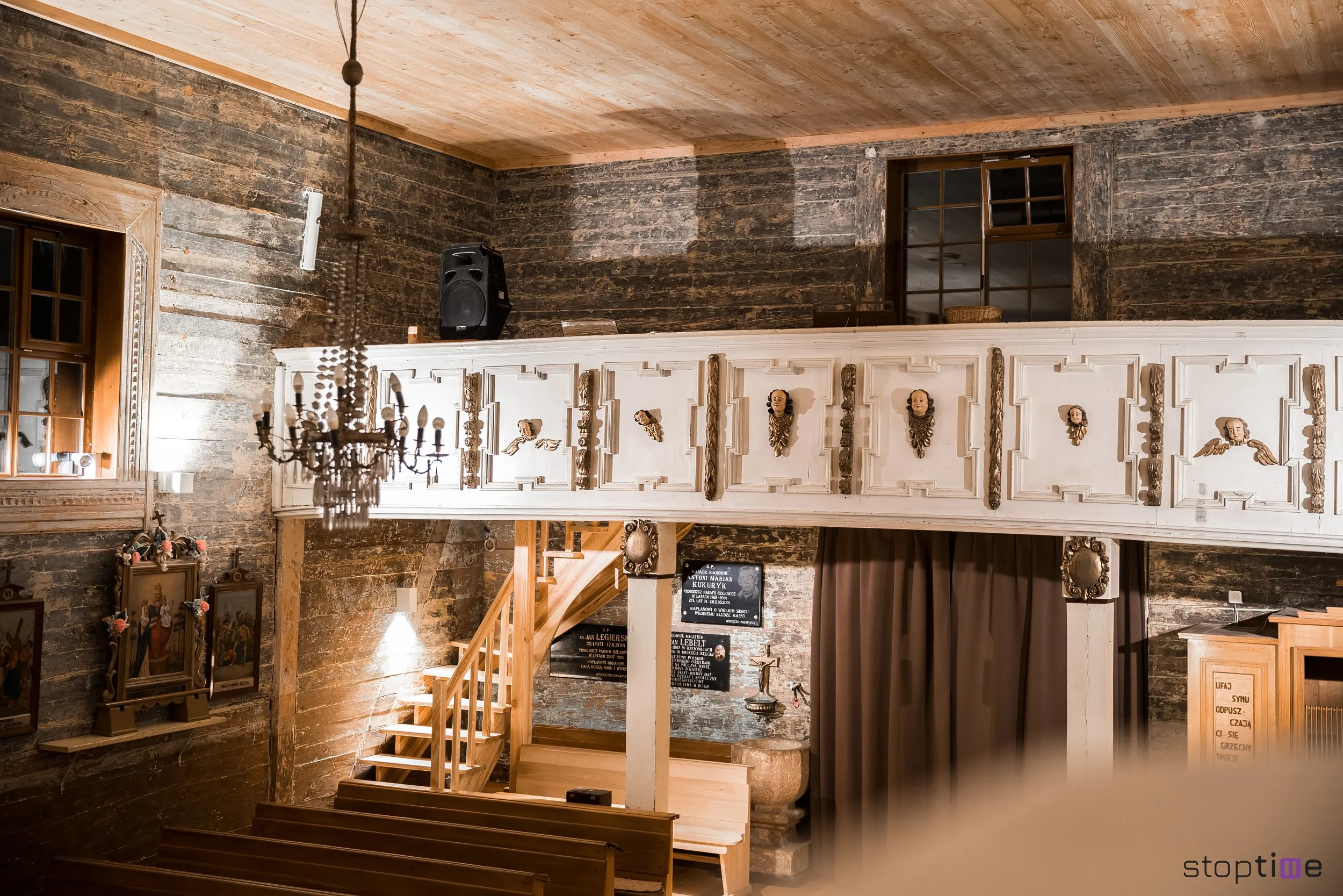 Chór muzyczny we wnętrzu kościoła w Rzejowicach z dekorowaną balustradą i drewnianymi schodami.