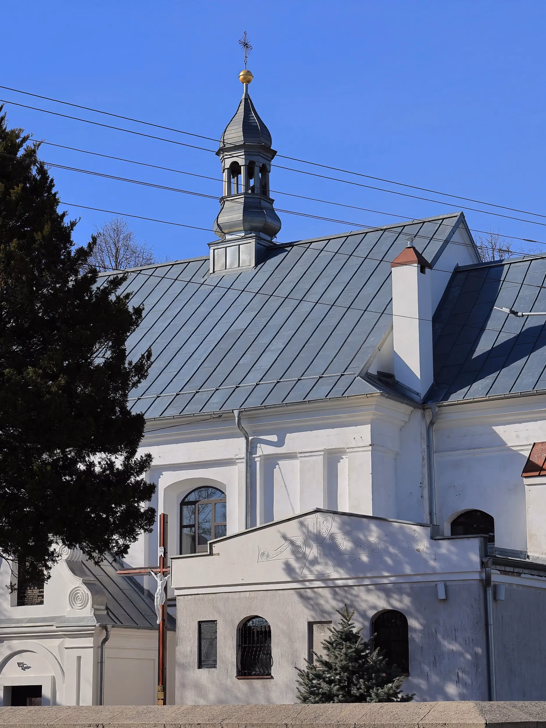 Boczna elewacja kościoła w Dmeninie z sygnaturką na dachu oraz przybudówką znajdującą się przy świątyni.