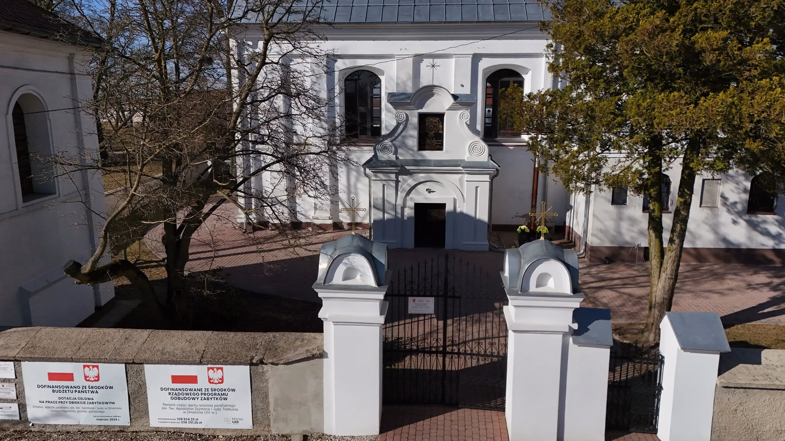 Widok z góry na główne wejście do kościoła w Dmeninie oraz bramę prowadzącą na teren przykościelny.