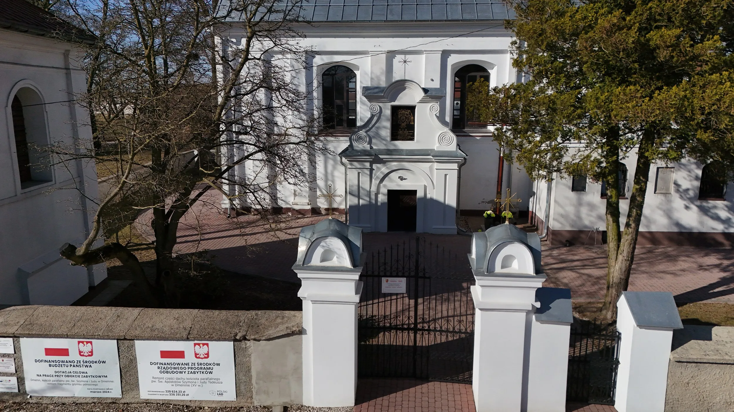 Widok z góry na główne wejście do kościoła w Dmeninie oraz bramę prowadzącą na teren przykościelny.