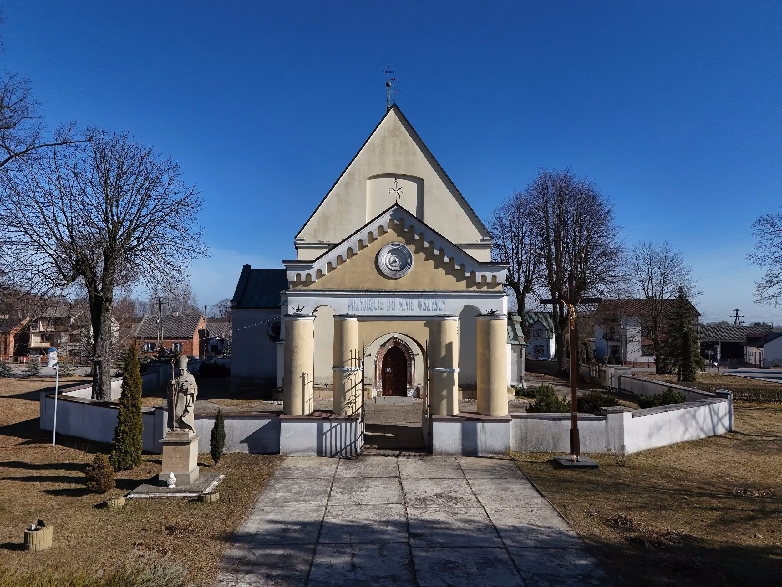 Kościół pw. św. Marcina w Kodrębie widziany od frontu. Przed wejściem znajduje się brama z kolumnami, figura świętego oraz krzyż misyjny.
