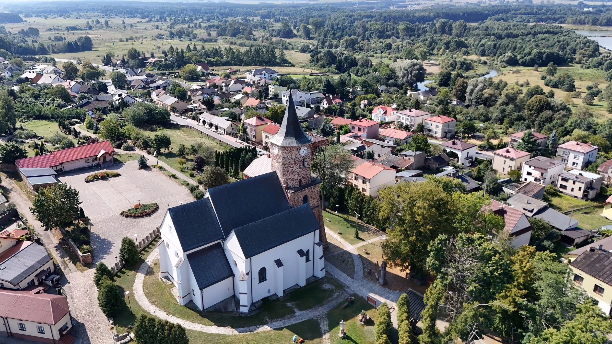 Widok z lotu ptaka na kościół św. Aleksego w Przedborzu oraz otaczającą zabudowę miasta, tereny zielone i dolinę Pilicy.