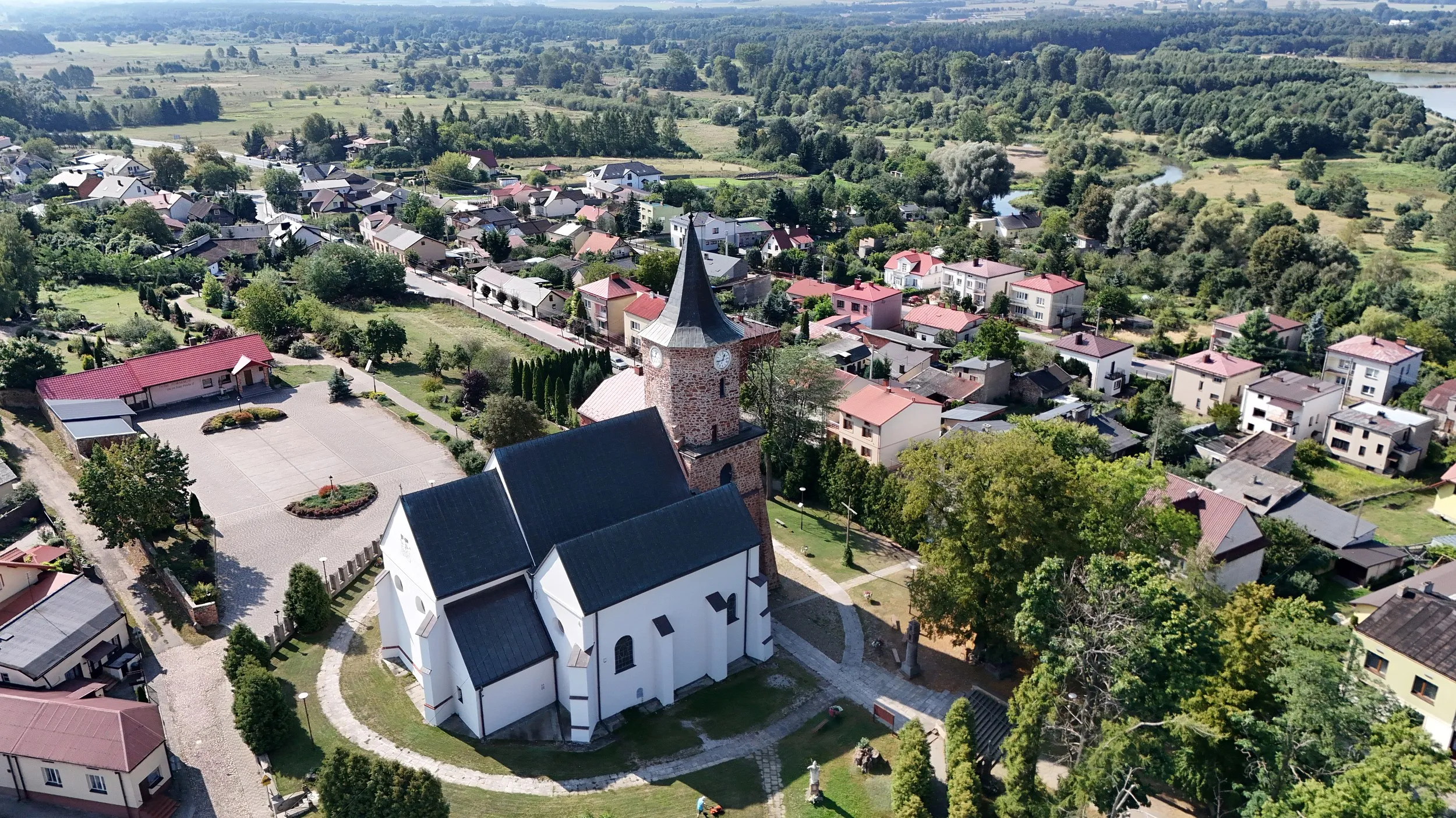 Widok z lotu ptaka na kościół św. Aleksego w Przedborzu oraz otaczającą zabudowę miasta, tereny zielone i dolinę Pilicy.