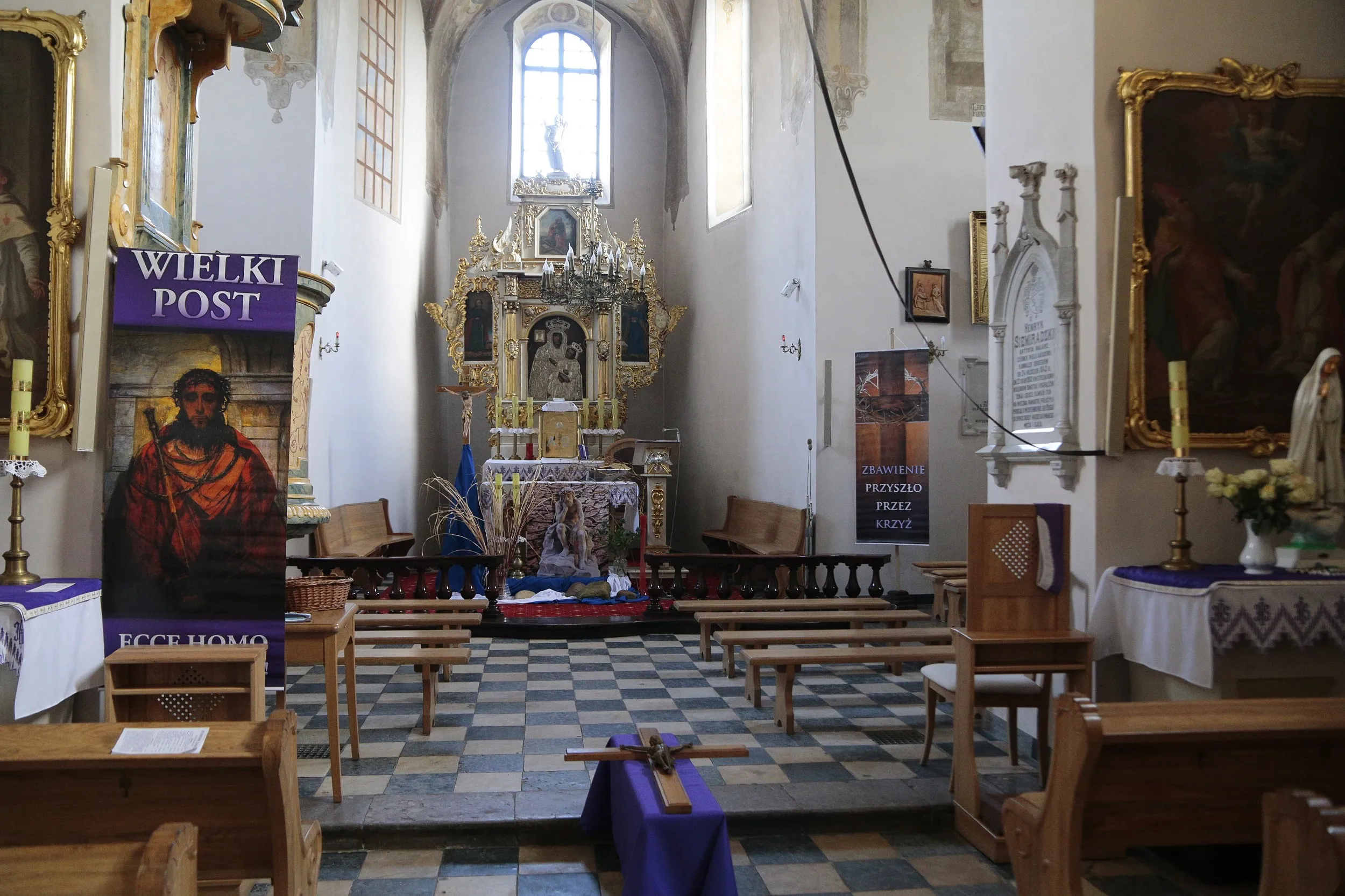 Wnętrze kościoła w Strzałkowie z widokiem na ołtarz główny. Widoczne ławki, dekoracje wielkopostne oraz zabytkowe wyposażenie świątyni.
