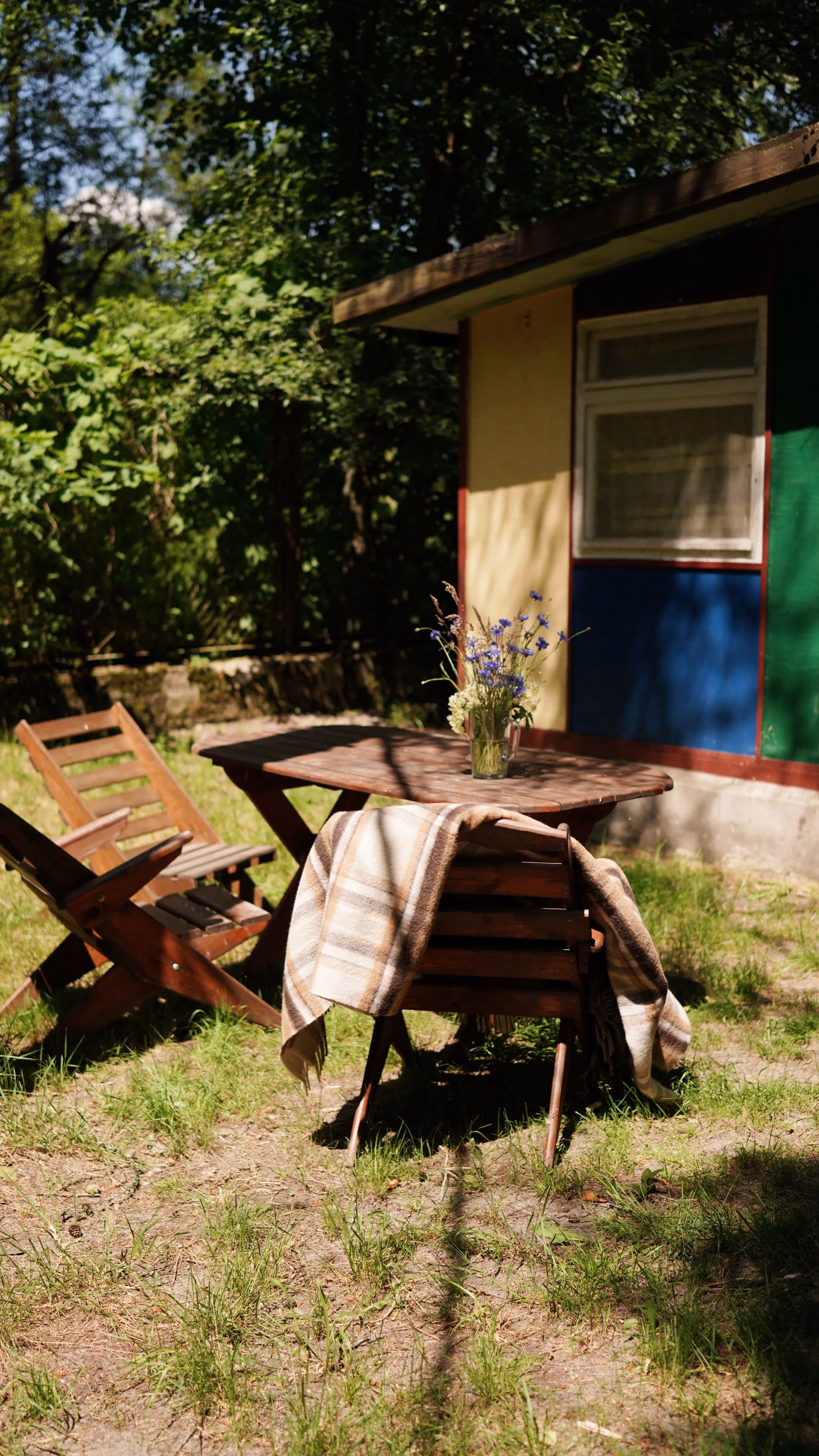 Drewniany stół i leżaki przy domku letniskowym, idealne miejsce do relaksu na świeżym powietrzu.