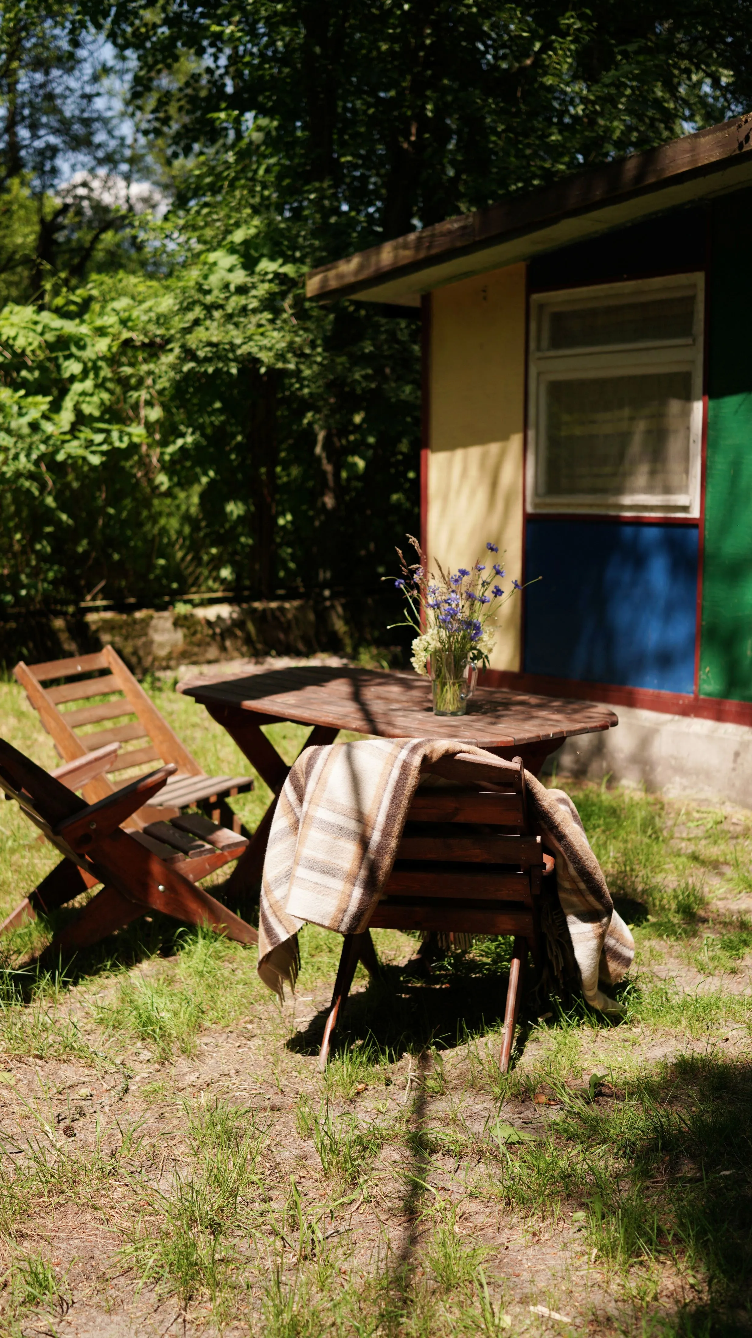 Drewniany stół i leżaki przy domku letniskowym, idealne miejsce do relaksu na świeżym powietrzu.