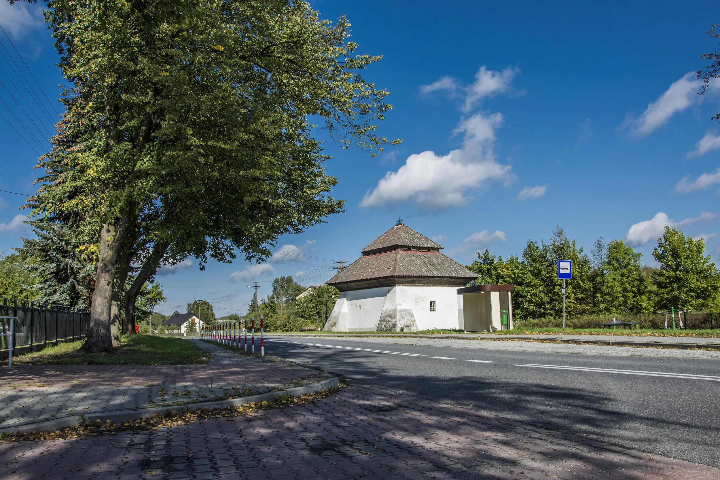 Kaplica ariańska w Silniczce widziana od strony drogi. Zabytkowy budynek o charakterystycznej bryle otoczony jest drzewami i zielenią.