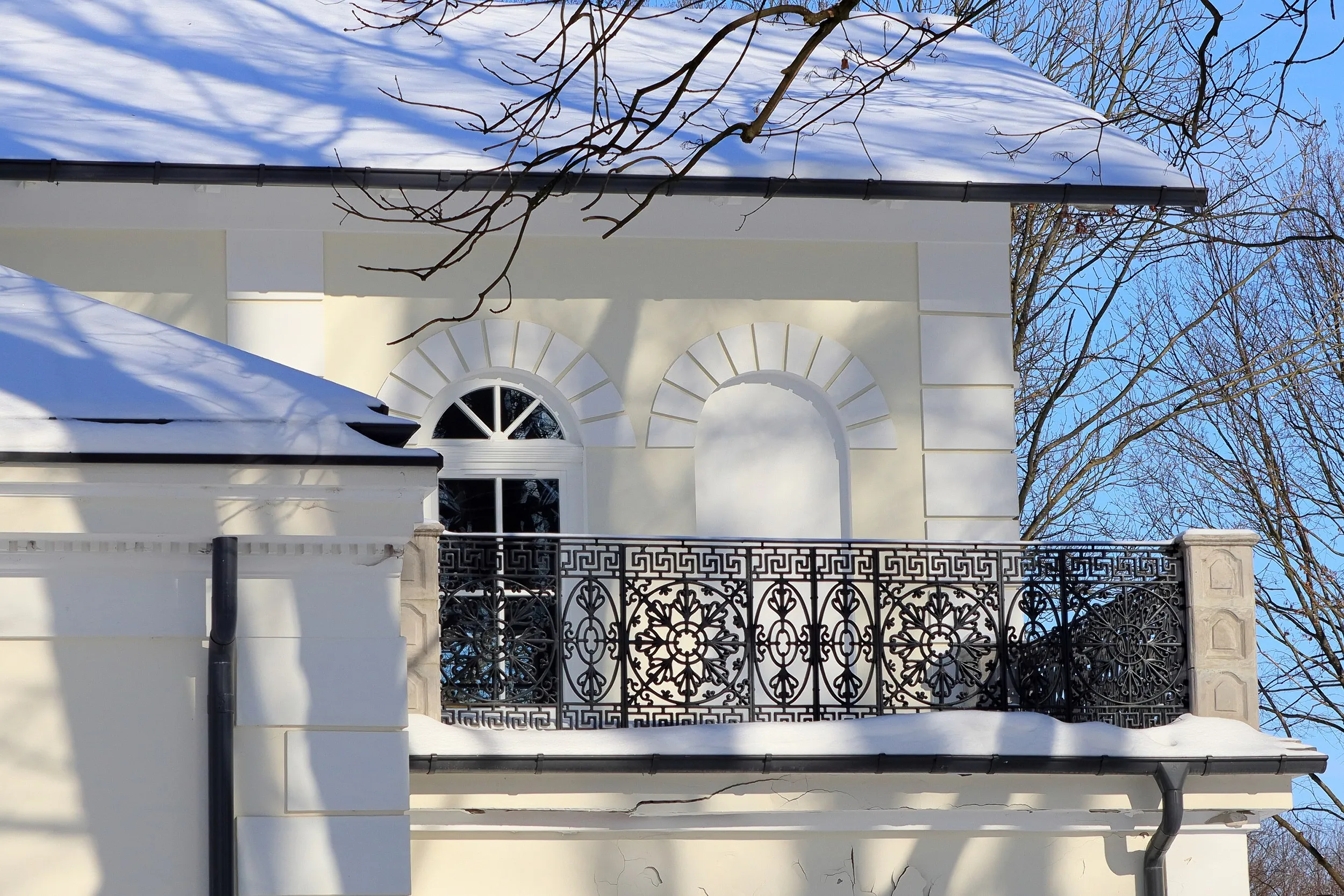 Fragment elewacji dworu w Żytnie. Widoczny balkon z ozdobną metalową balustradą oraz okno zwieńczone dekoracyjnym obramieniem.
