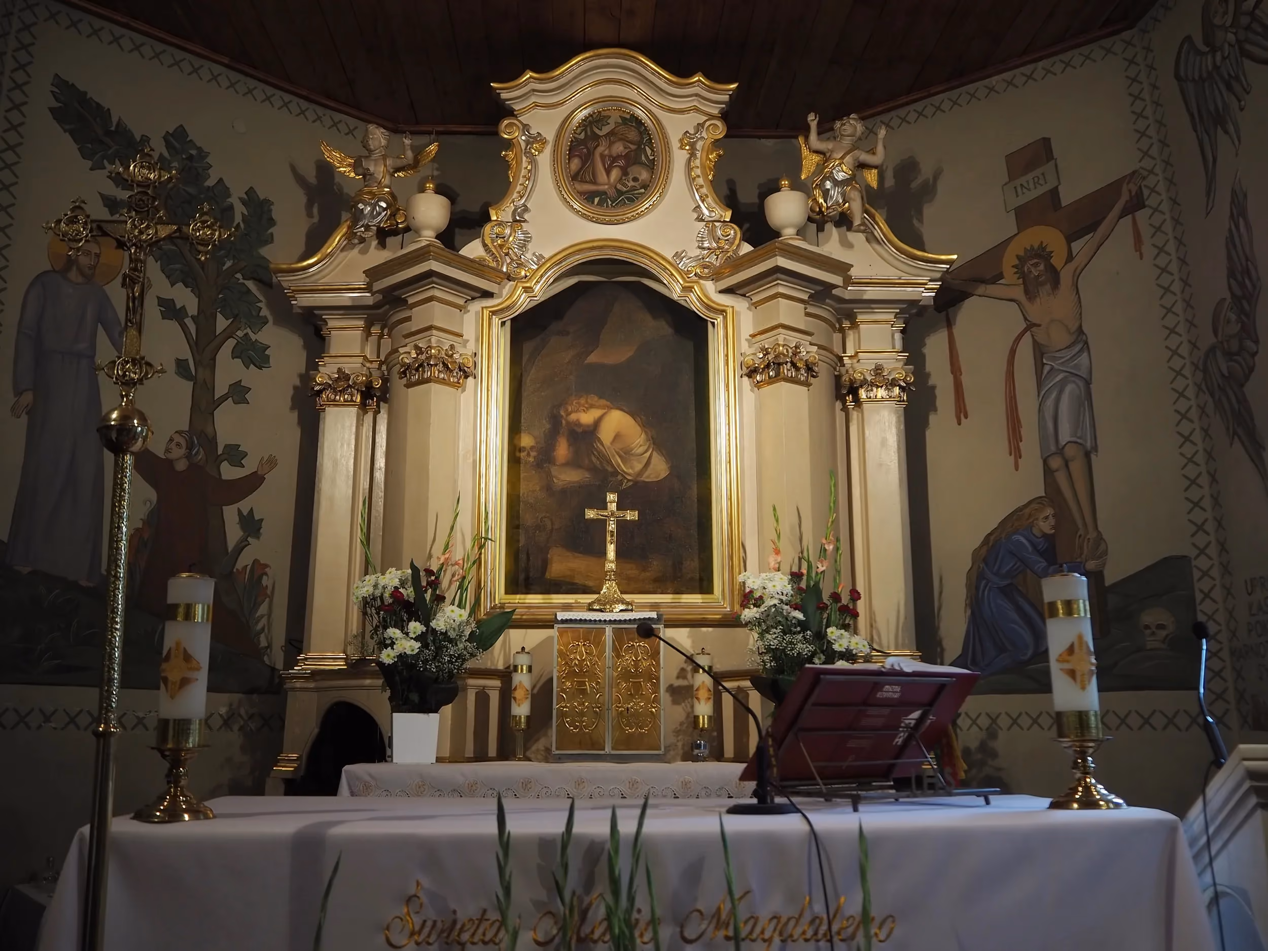 Barokowy ołtarz główny w kościele św. Marii Magdaleny w Radomsku z obrazem patronki, krucyfiksem oraz dekoracją kwiatową.
