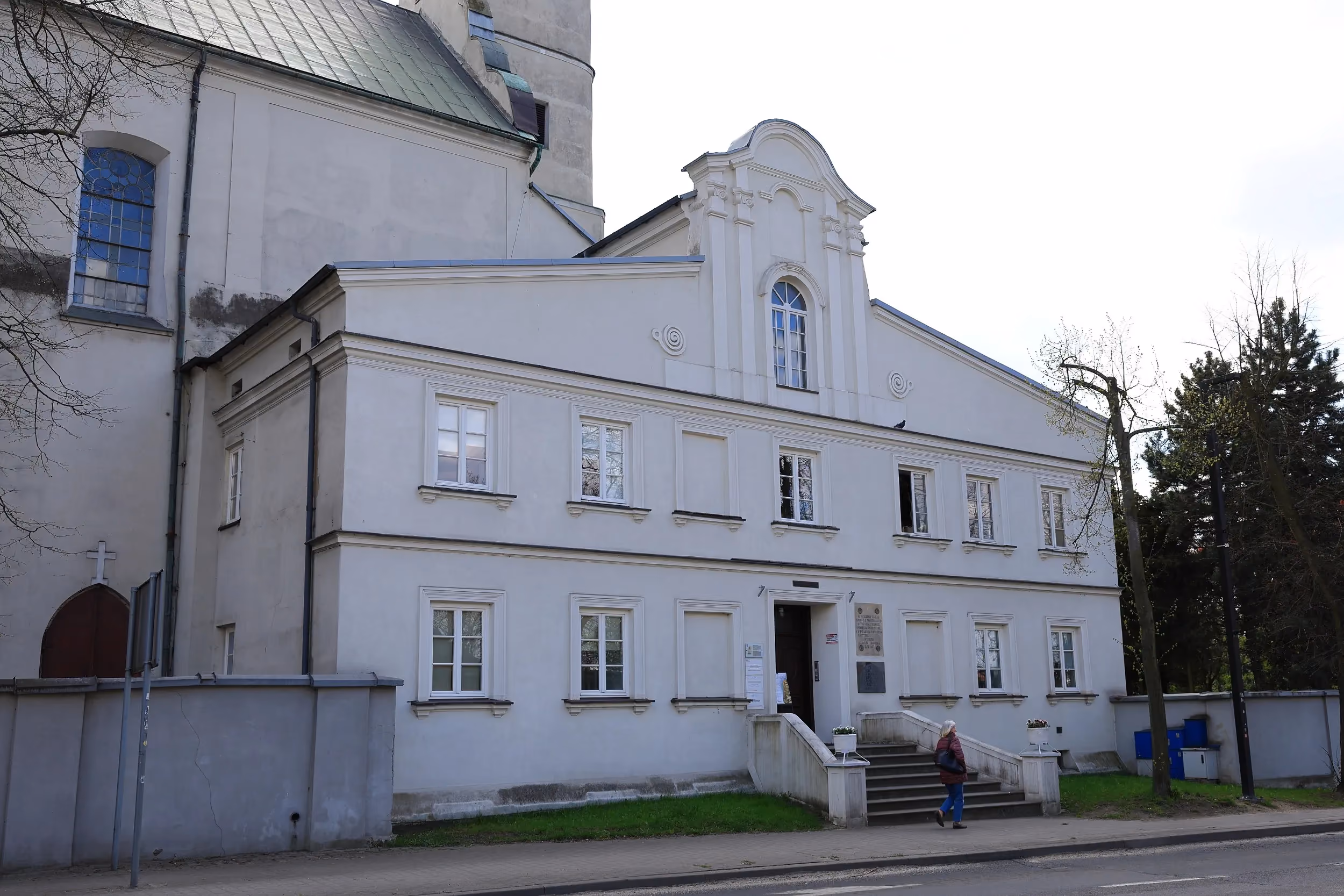 Budynek klasztoru franciszkanów w Radomsku. Dwukondygnacyjna, jasna elewacja z wejściem głównym i schodami od strony ulicy.