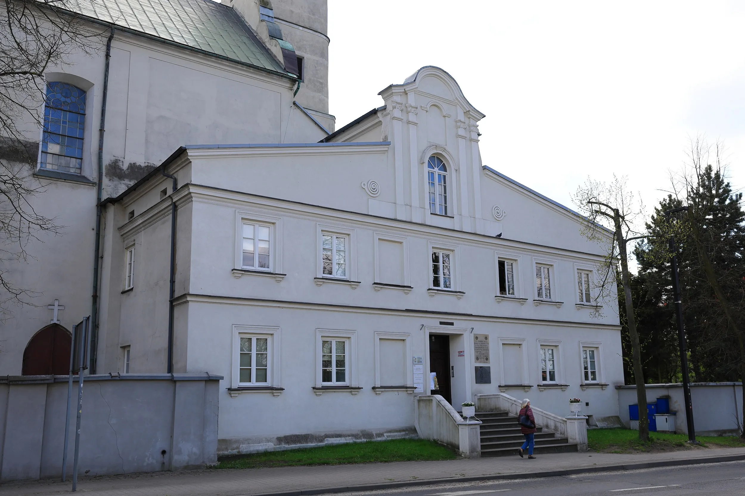 Budynek klasztoru franciszkanów w Radomsku. Dwukondygnacyjna, jasna elewacja z wejściem głównym i schodami od strony ulicy.