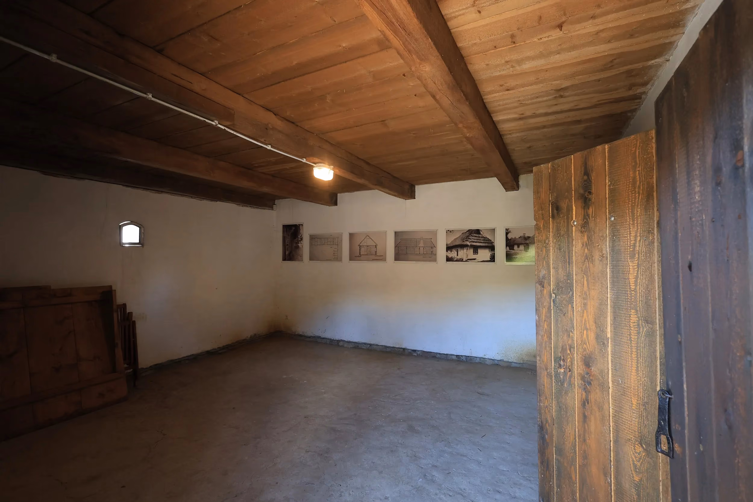 Pomieszczenie ekspozycyjne w zabytkowej chacie tatarskiej w Radomsku z fotografiami dokumentującymi historię obiektu.