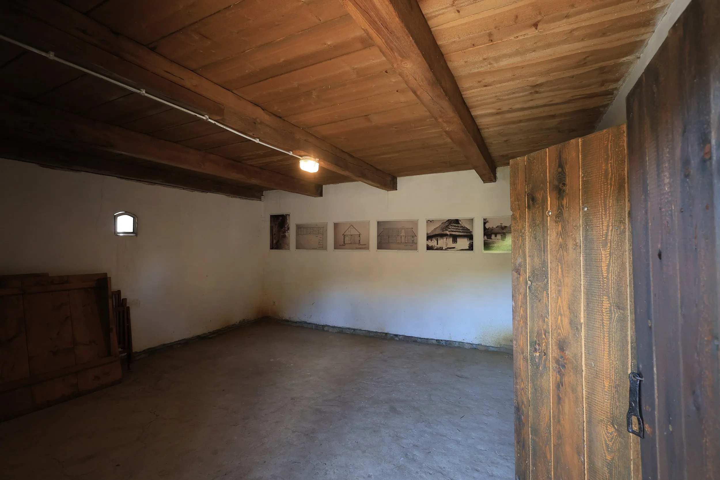 Pomieszczenie ekspozycyjne w zabytkowej chacie tatarskiej w Radomsku z fotografiami dokumentującymi historię obiektu.